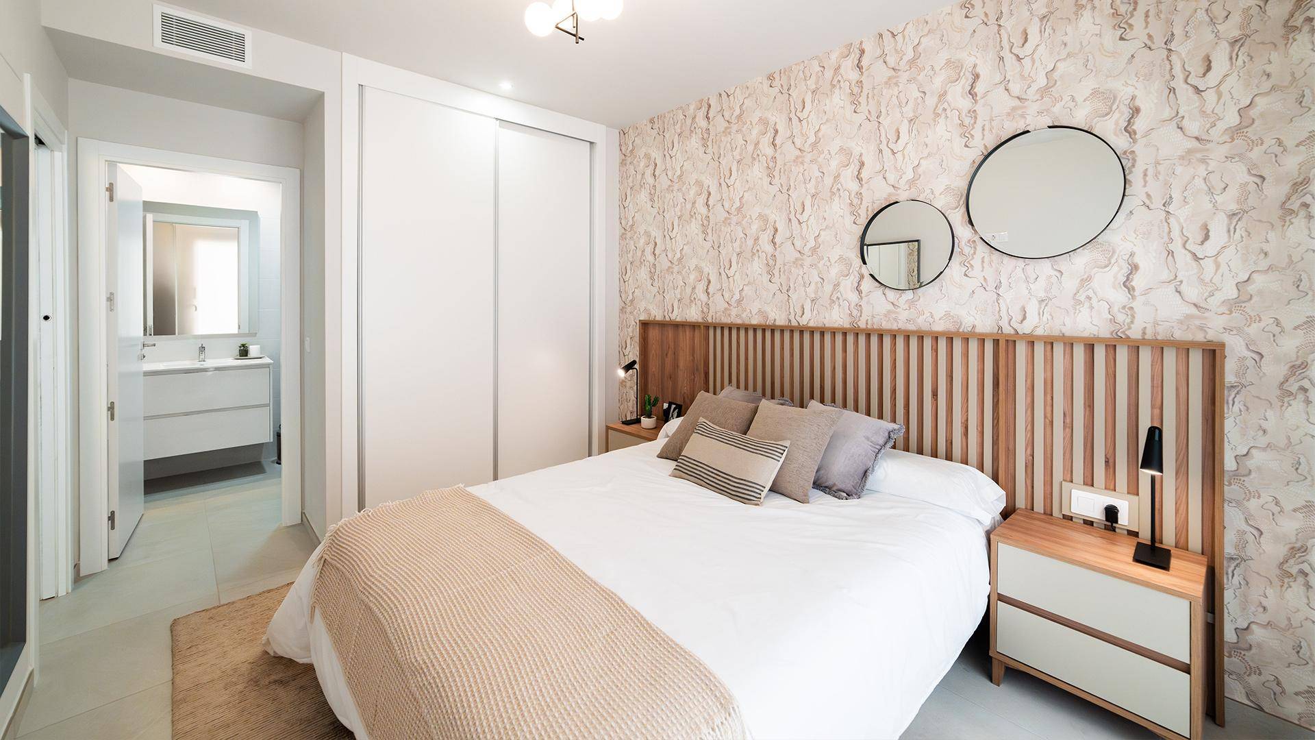 Gemütliches Schlafzimmer mit Holzkopfteil, gemusterter Tapete und Einbauschränken.