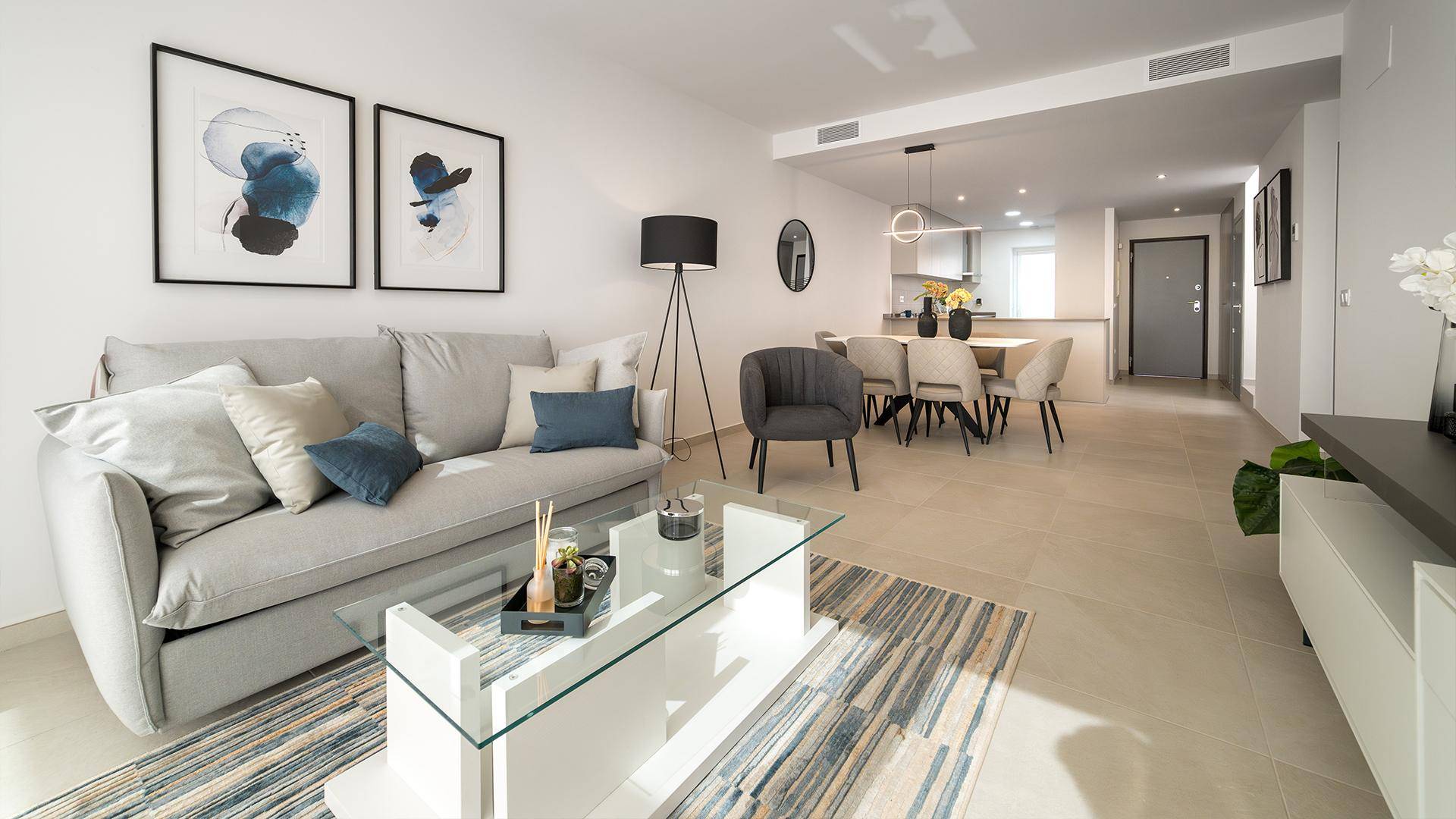 Helles, offenes Wohn-Esszimmer mit modernen Möbeln, Fliesenboden und Kunstwerken.