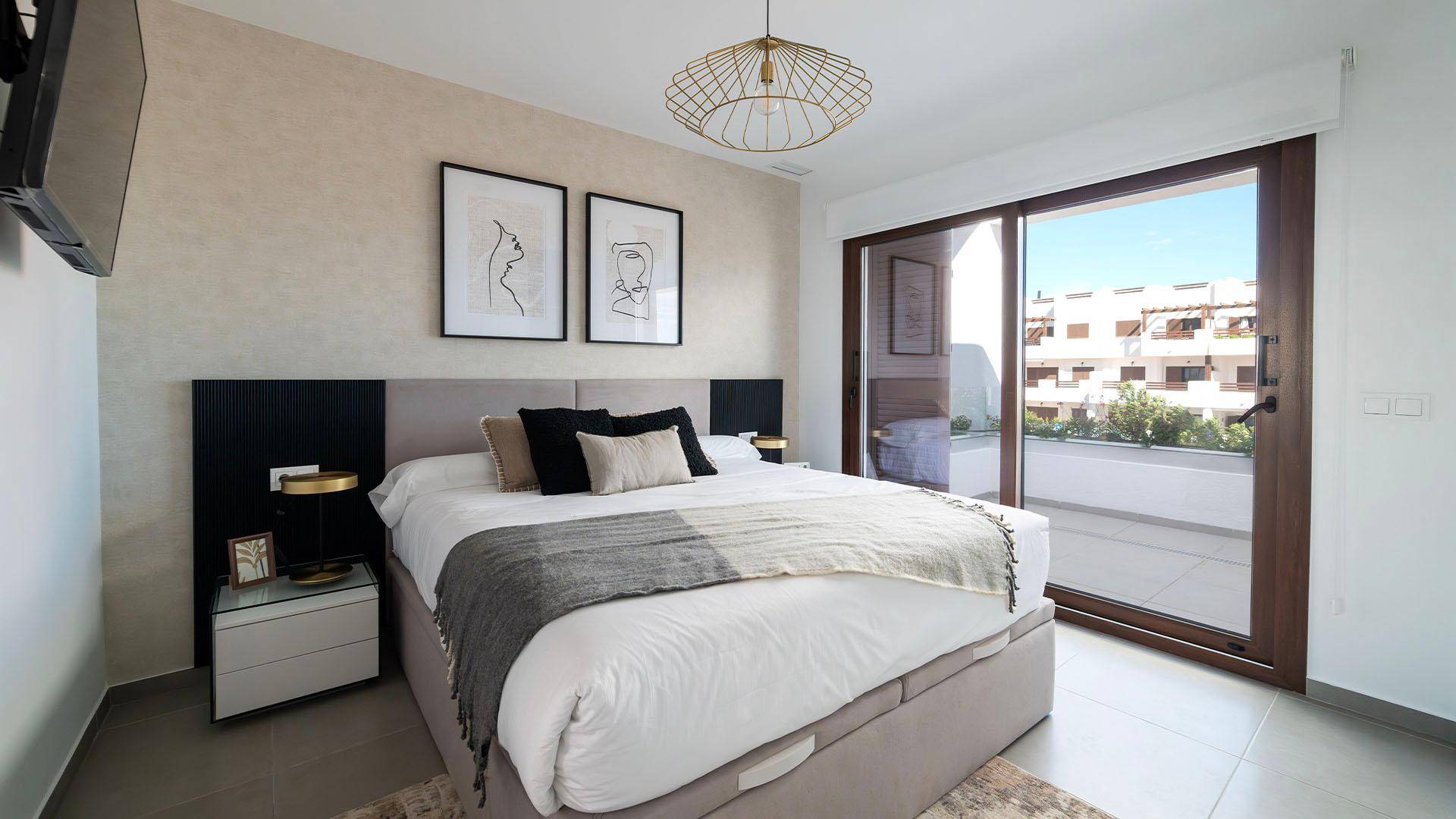 Helles Schlafzimmer mit Doppelbett, moderner Einrichtung und Zugang zu einem Balkon.