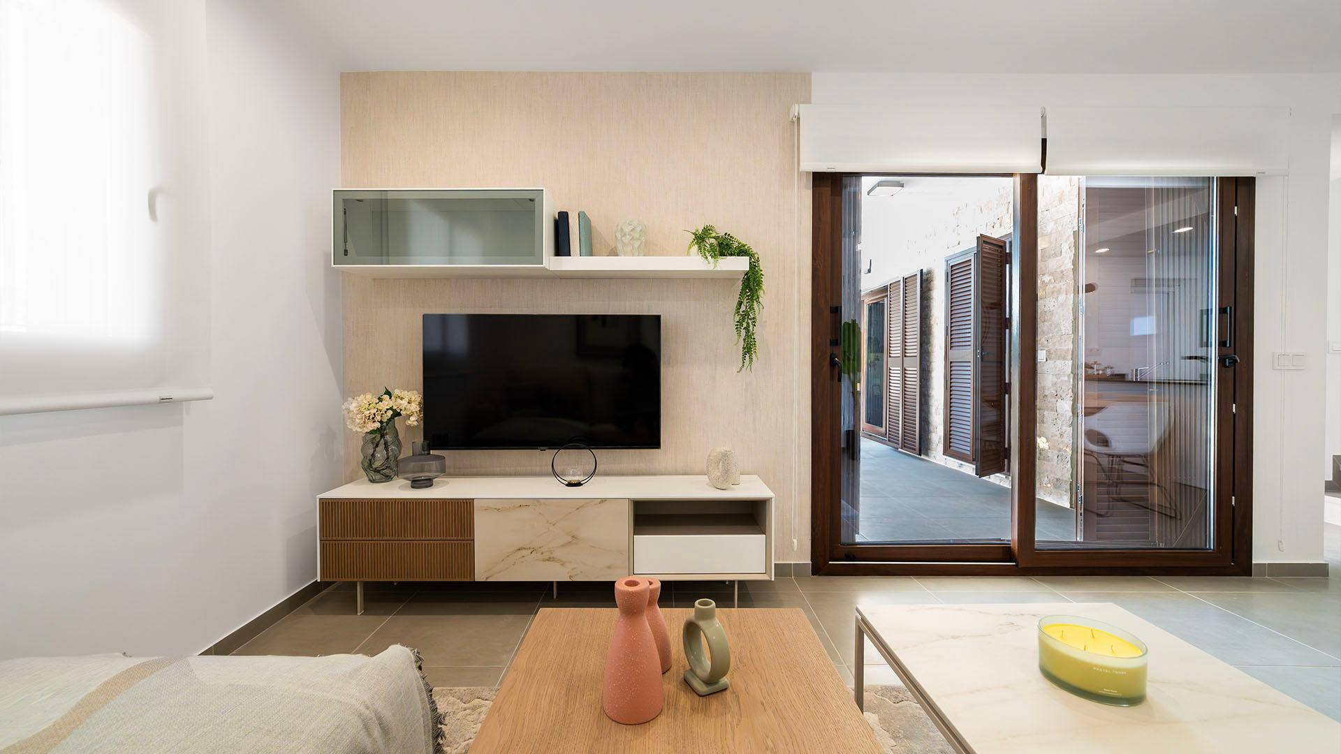 Helles Wohnzimmer mit modernen Möbeln, Fliesenboden und Zugang zur Terrasse.