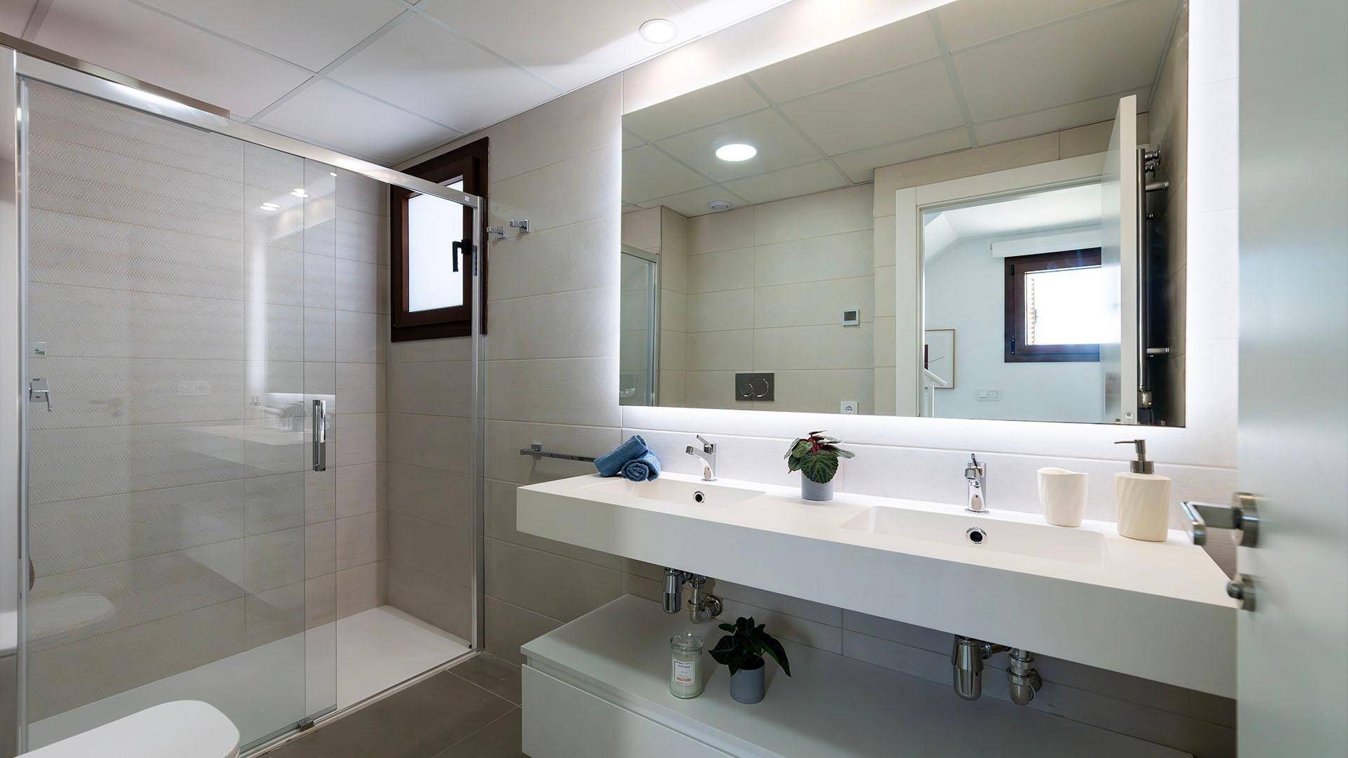 Modernes Badezimmer mit Doppelwaschbecken, großer Spiegelfläche und begehbarer Dusche.