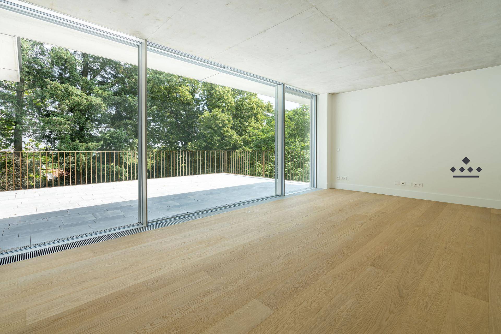 Geräumiger Wohnbereich mit hellem Parkettboden und bodentiefen Fenstern mit Zugang zur Terrasse.