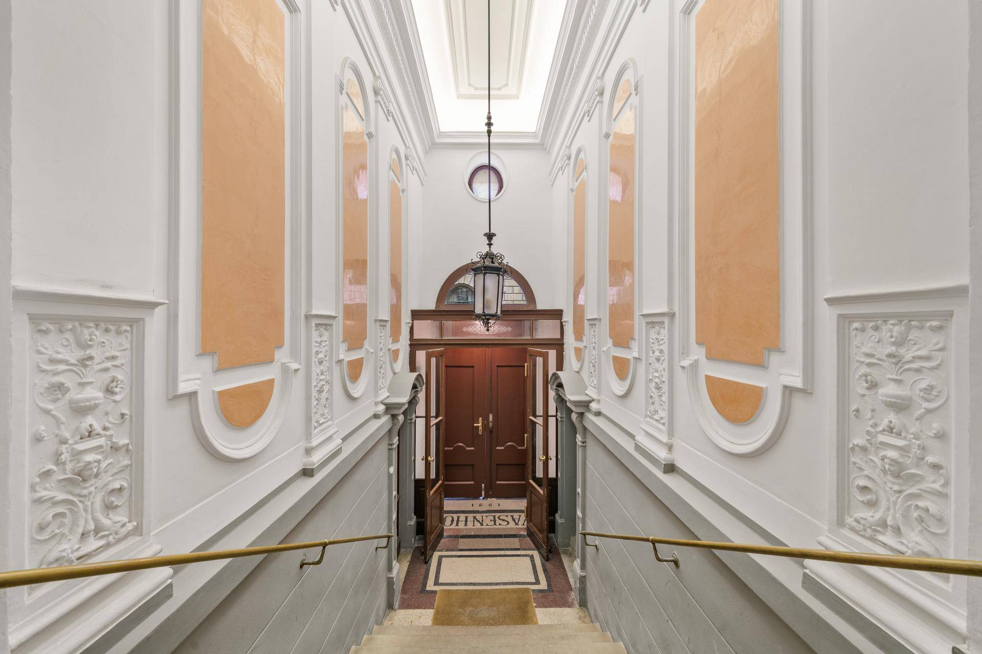 Prunkvolles Treppenhaus mit Stuckverzierungen, hohen Decken und historischem Charme.