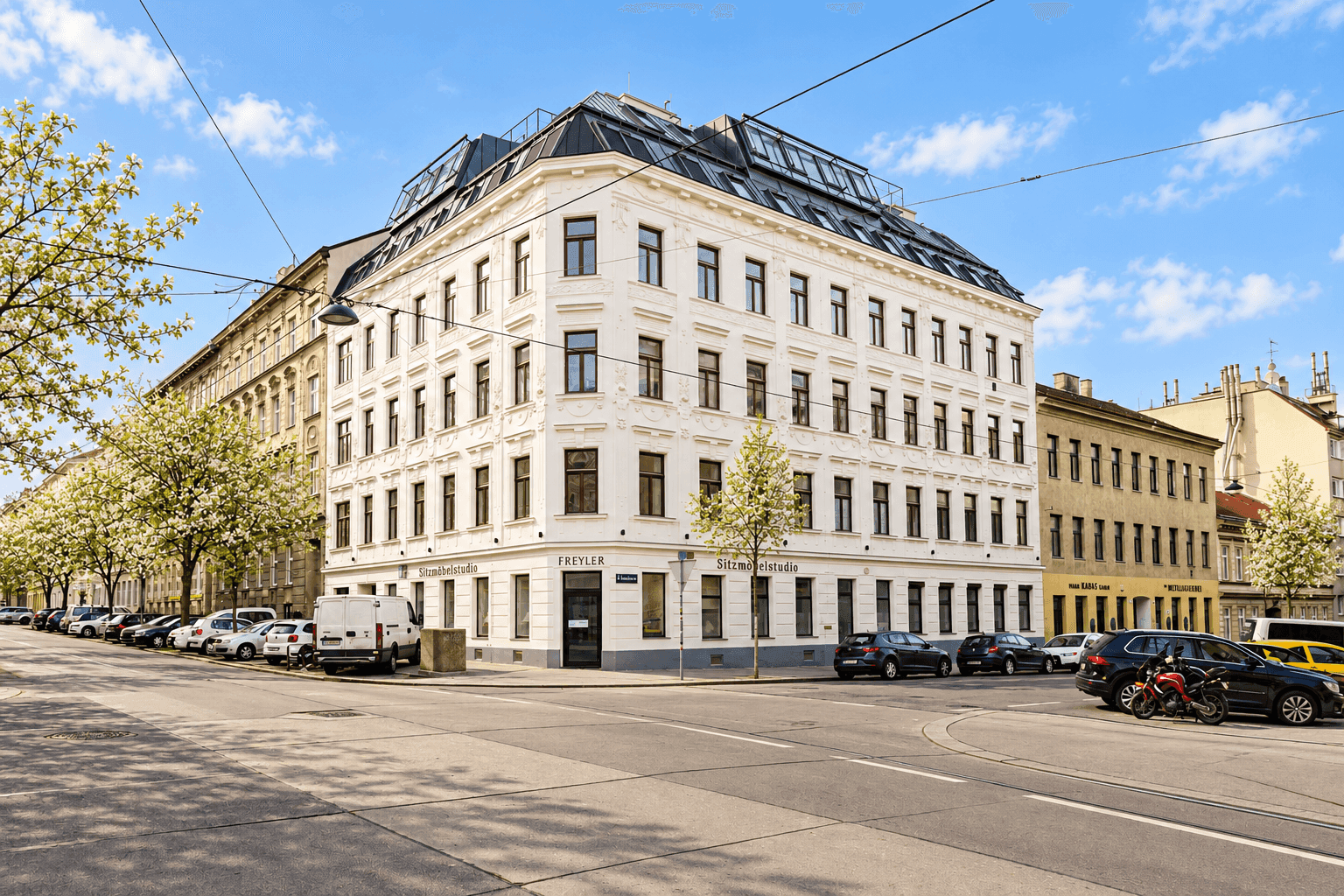 Sonnige Frühlingsstraße mit grünen Bäumen und Tramgleisen