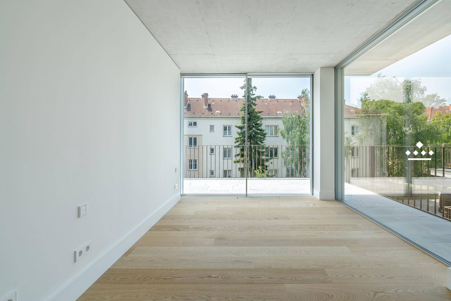 Heller Wohnraum mit Holzboden und großen Fenstern, die einen Blick auf die Stadt bieten.