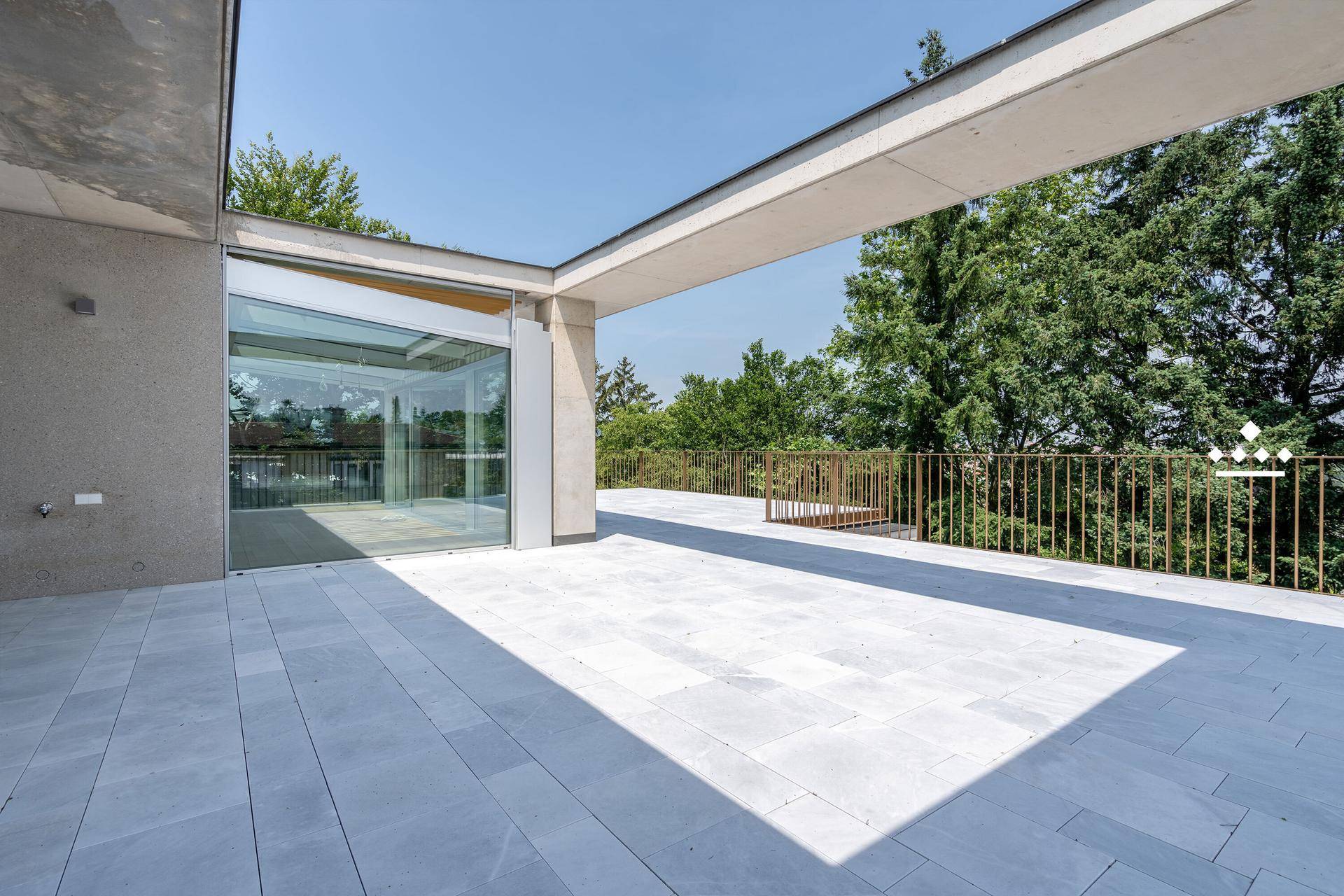 Weitläufige Terrasse mit modernen Fliesen und umgeben von üppigem Grün.