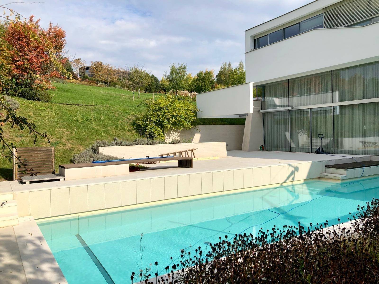 Außenbereich mit großem Swimmingpool und Liegeflächen, umgeben von einer grünen Hügellandschaft.