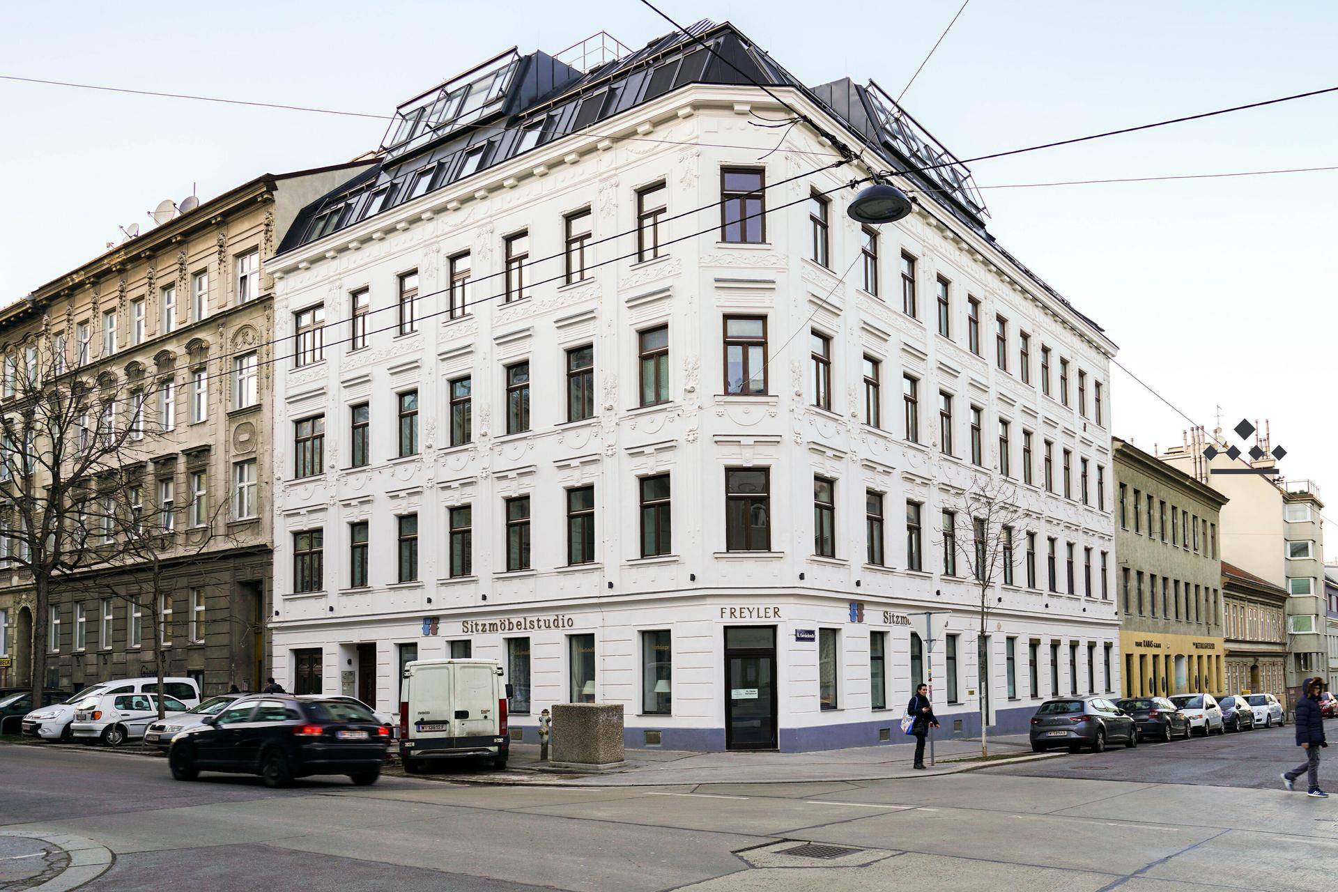 Historisches Eckgebäude mit moderner Dachaufstockung in urbaner Umgebung.