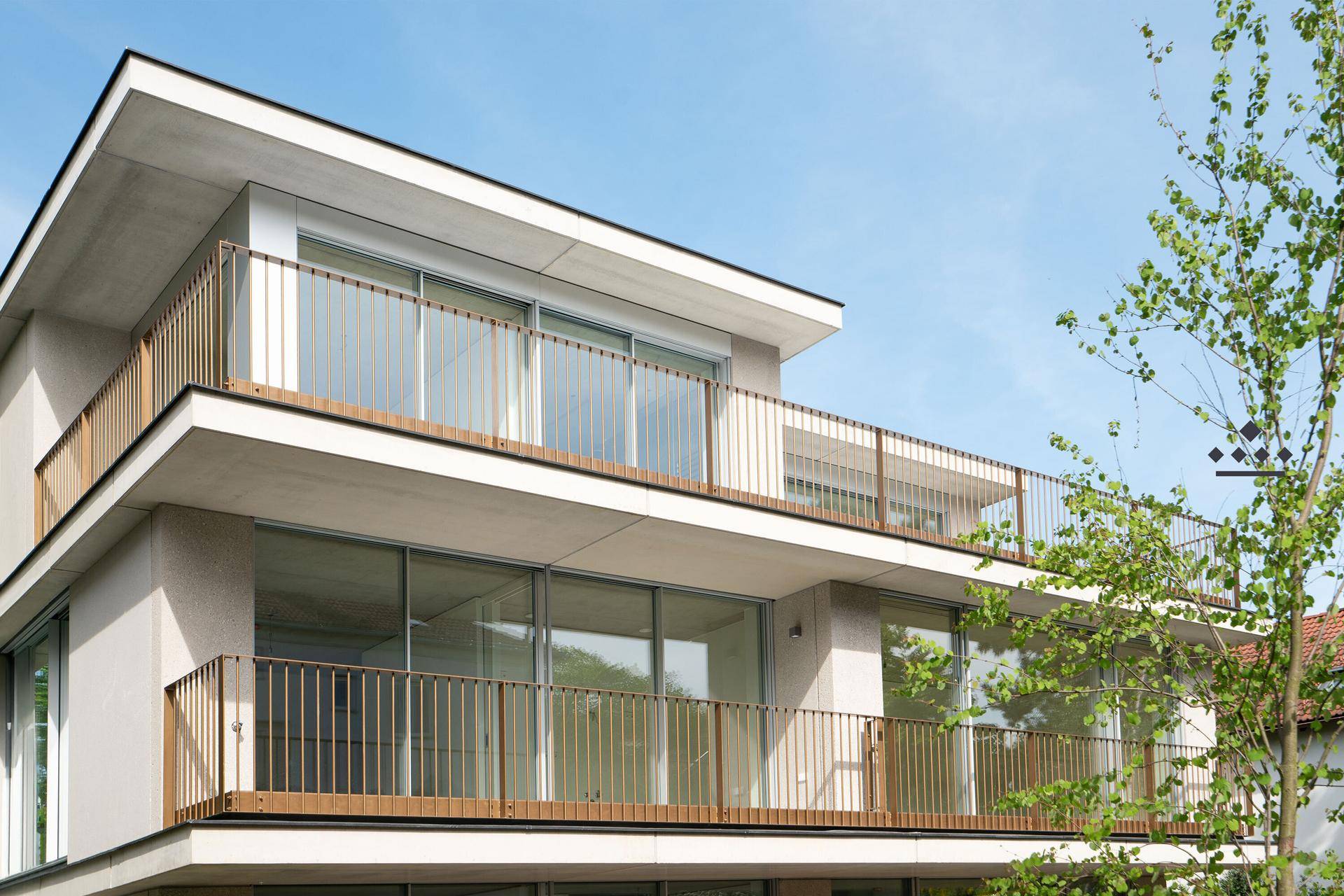 Fassade eines modernen Neubaus mit großen Glasfronten und eleganten Balkongeländern.