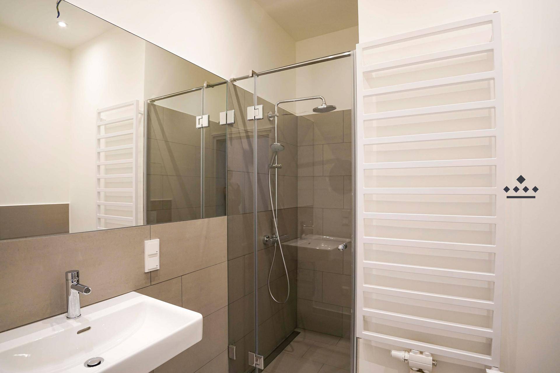 Modernes Badezimmer mit begehbarer Dusche, großem Spiegel und beheiztem Handtuchhalter.