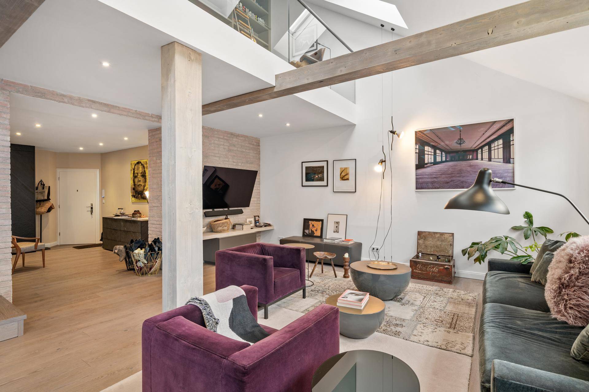 Stilvolles Wohnzimmer mit hohen Decken, Holzbalken und Zugang zum Eingangsbereich.