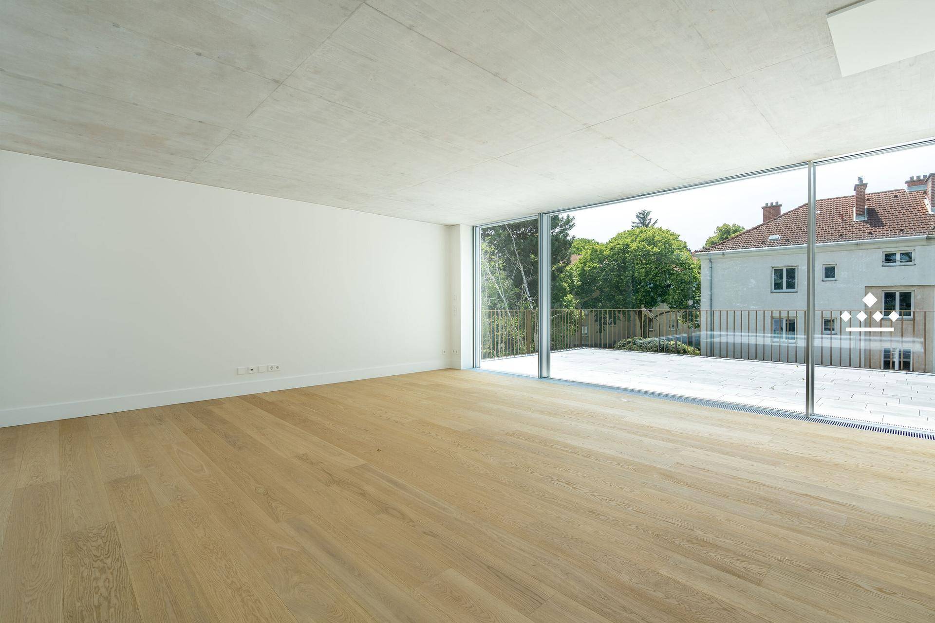 Geräumiger, heller Wohnbereich mit Holzboden und Zugang zu einer großen Außenterrasse.