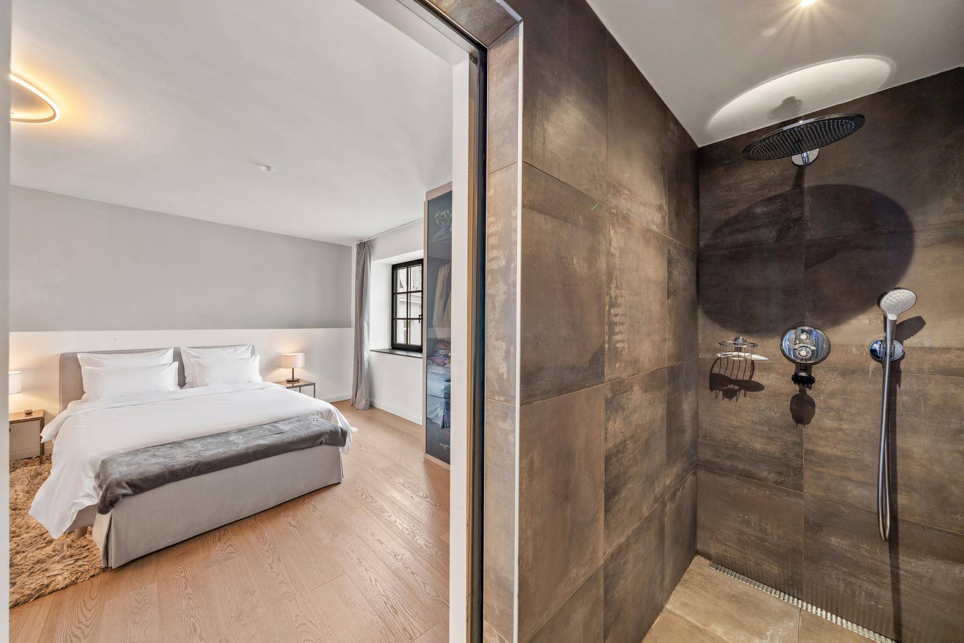 Schlafzimmer und modernes Badezimmer mit begehbarer Dusche und Holzboden.
