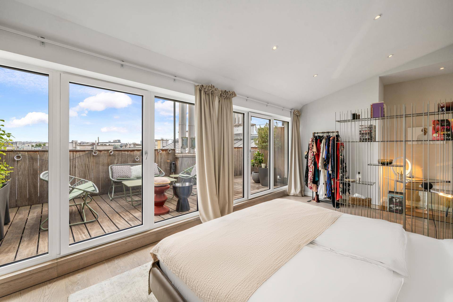 Schlafzimmer mit großen Fenstern, die Zugang zu einer privaten Dachterrasse bieten.