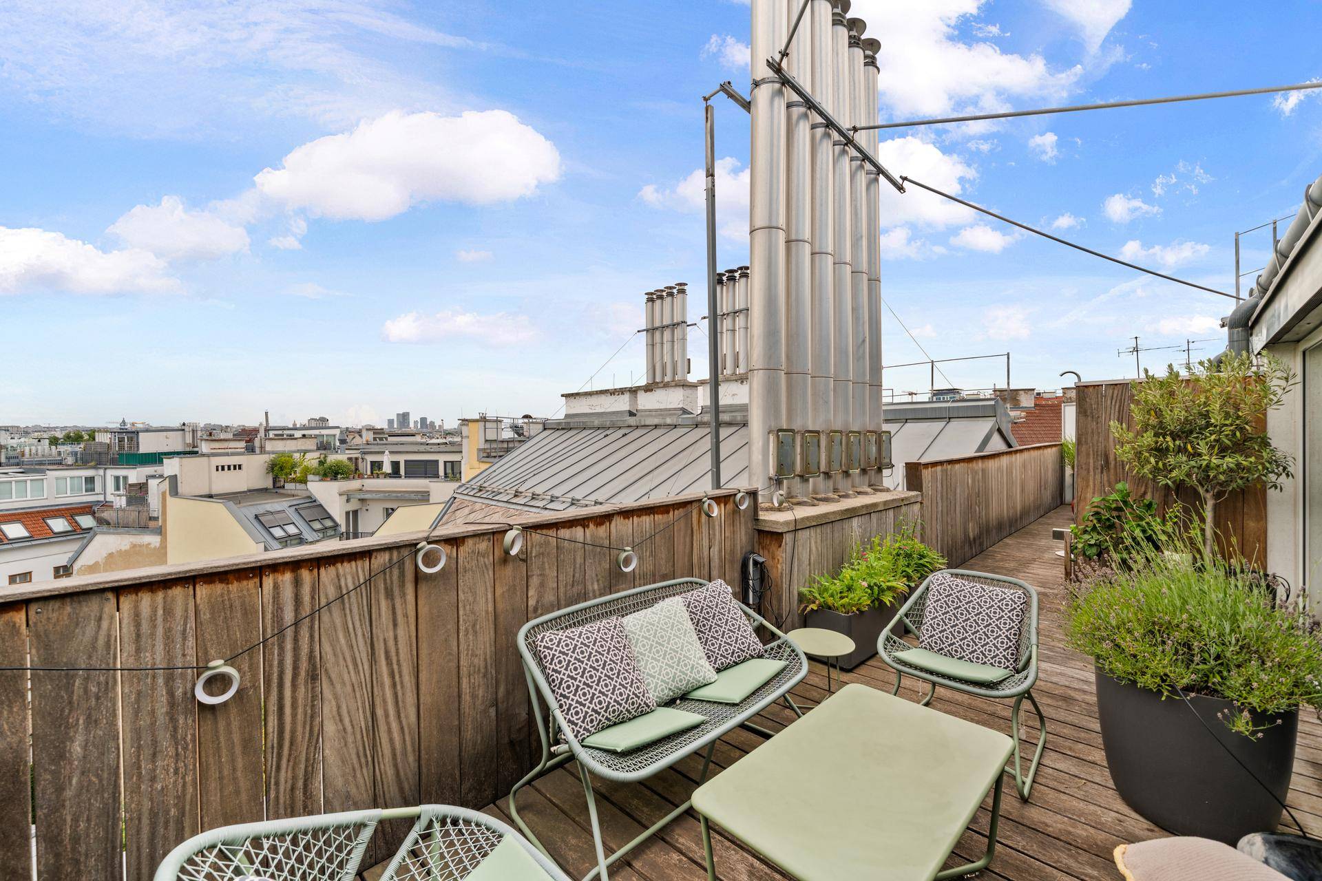 Geräumige Dachterrasse mit Sitzgelegenheiten, Pflanzen und weitem Stadtblick.