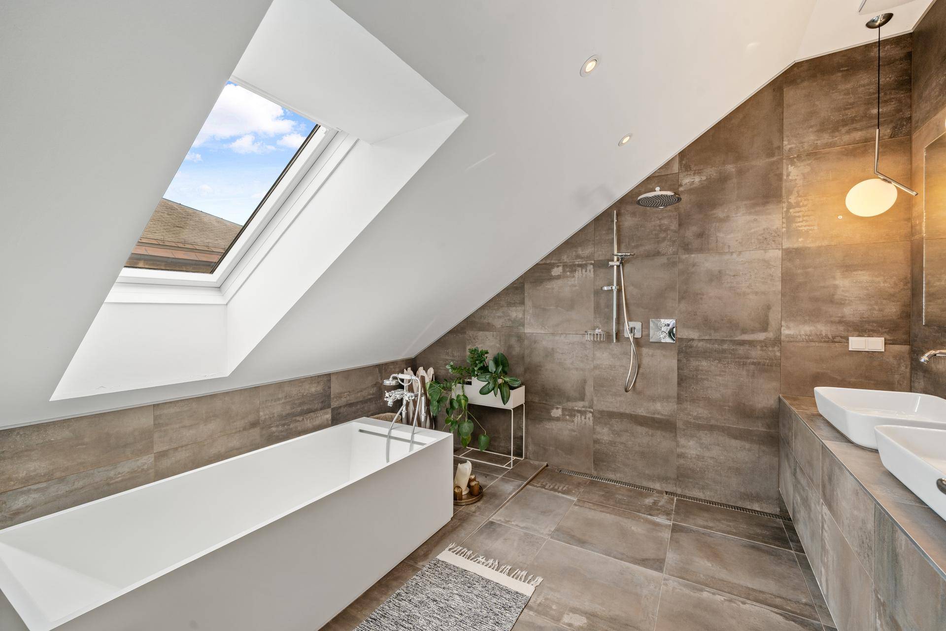 Modernes Badezimmer im Dachgeschoss mit freistehender Badewanne und Dachfenster.