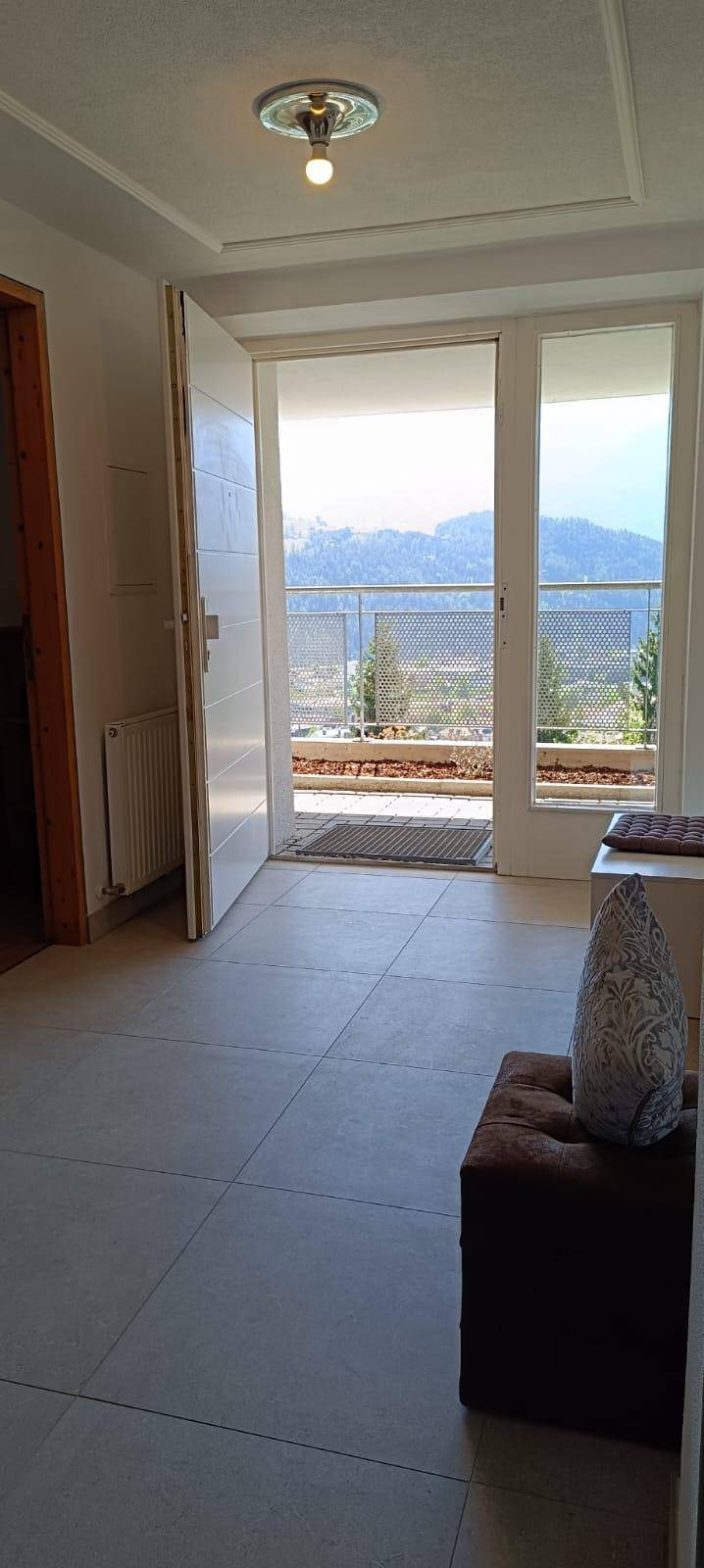 Heller Flur mit Zugang zu einem Balkon, der einen weiten Blick auf die Berge bietet.