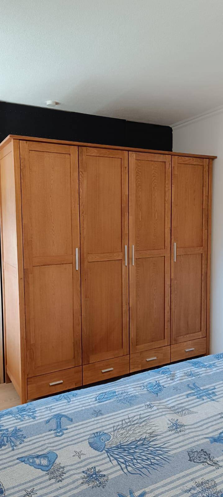 Schlafzimmer mit großem Holzschrank und passender Bettwäsche, bietet viel Stauraum.
