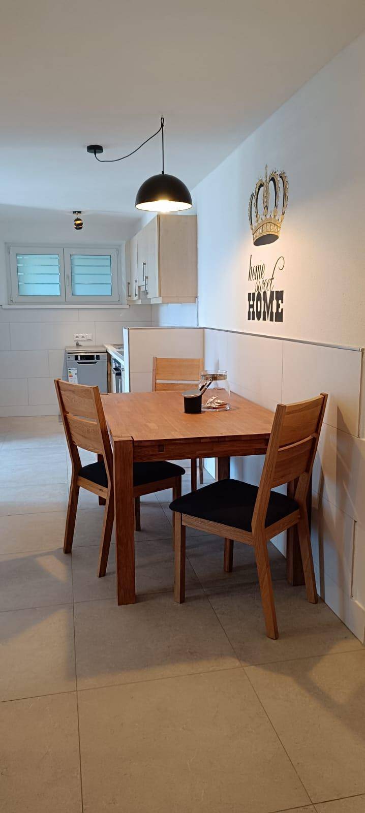 Essbereich mit Holztisch und Stühlen, offen zur Küche, mit moderner Wanddekoration.