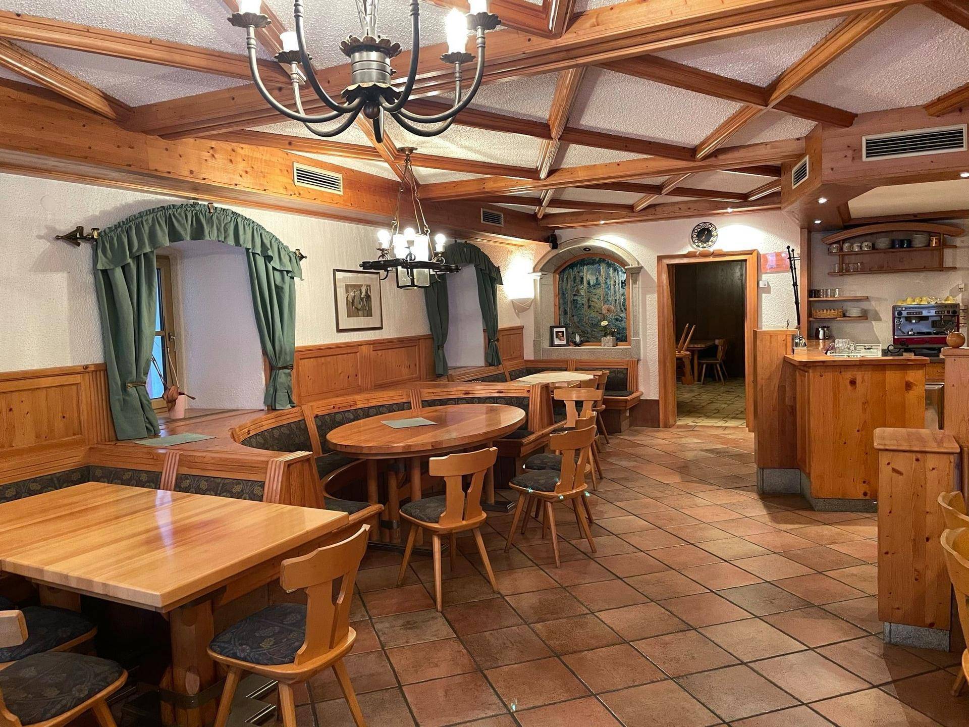 Gemütlicher Speisesaal mit traditionellen Holzbänken, Tischen und Terrakottafliesen, einladend und rustikal.