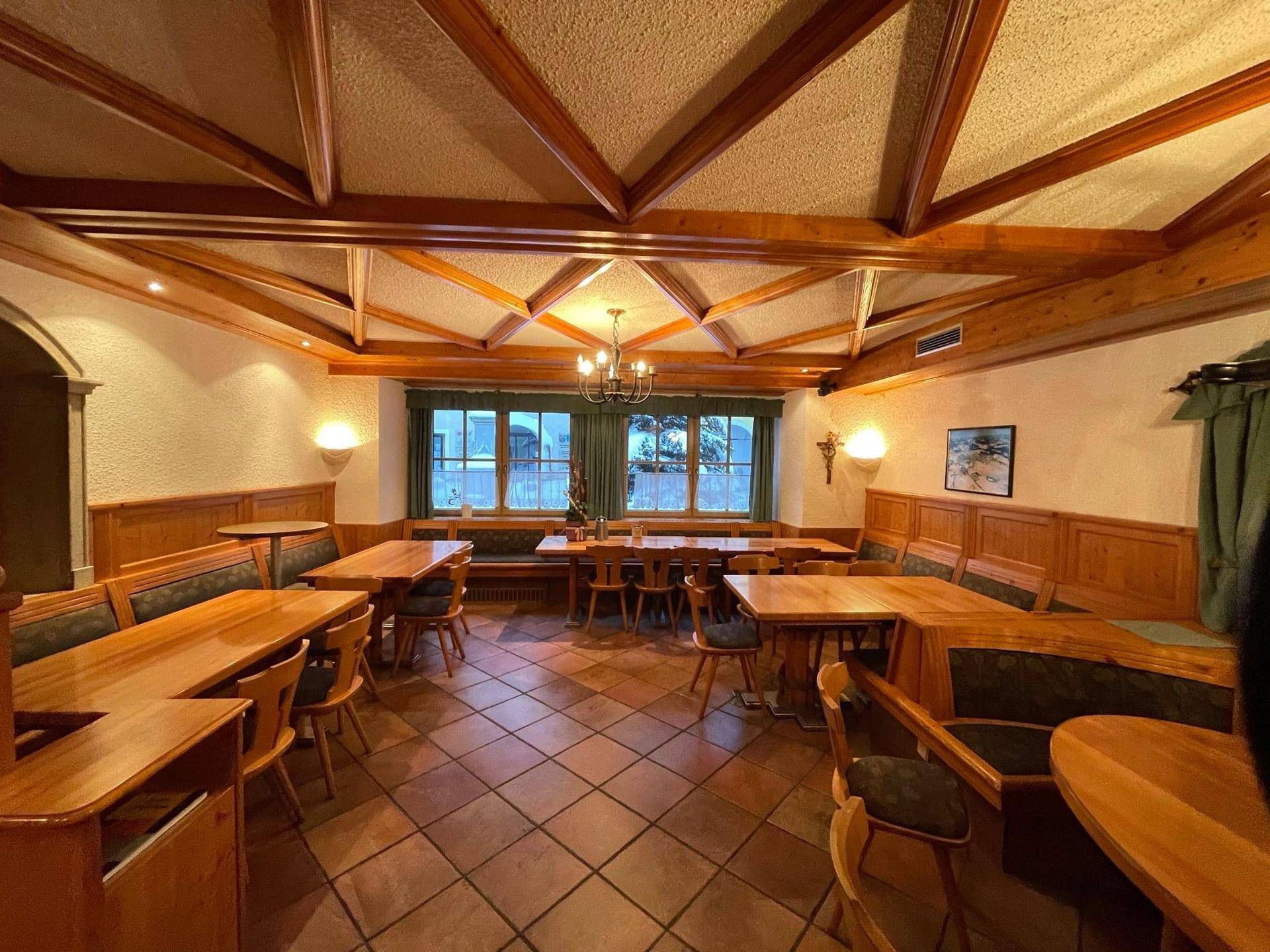 Heller Speisesaal mit Holztischen, gepolsterten Bänken und großen Fenstern, ideal für Gruppen.