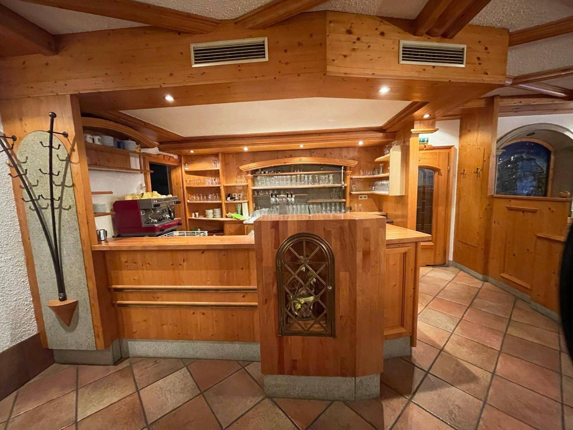 Rustikale Bar mit Holzeinrichtung, Theke und Regalen voller Gläser, ideal für gesellige Abende.