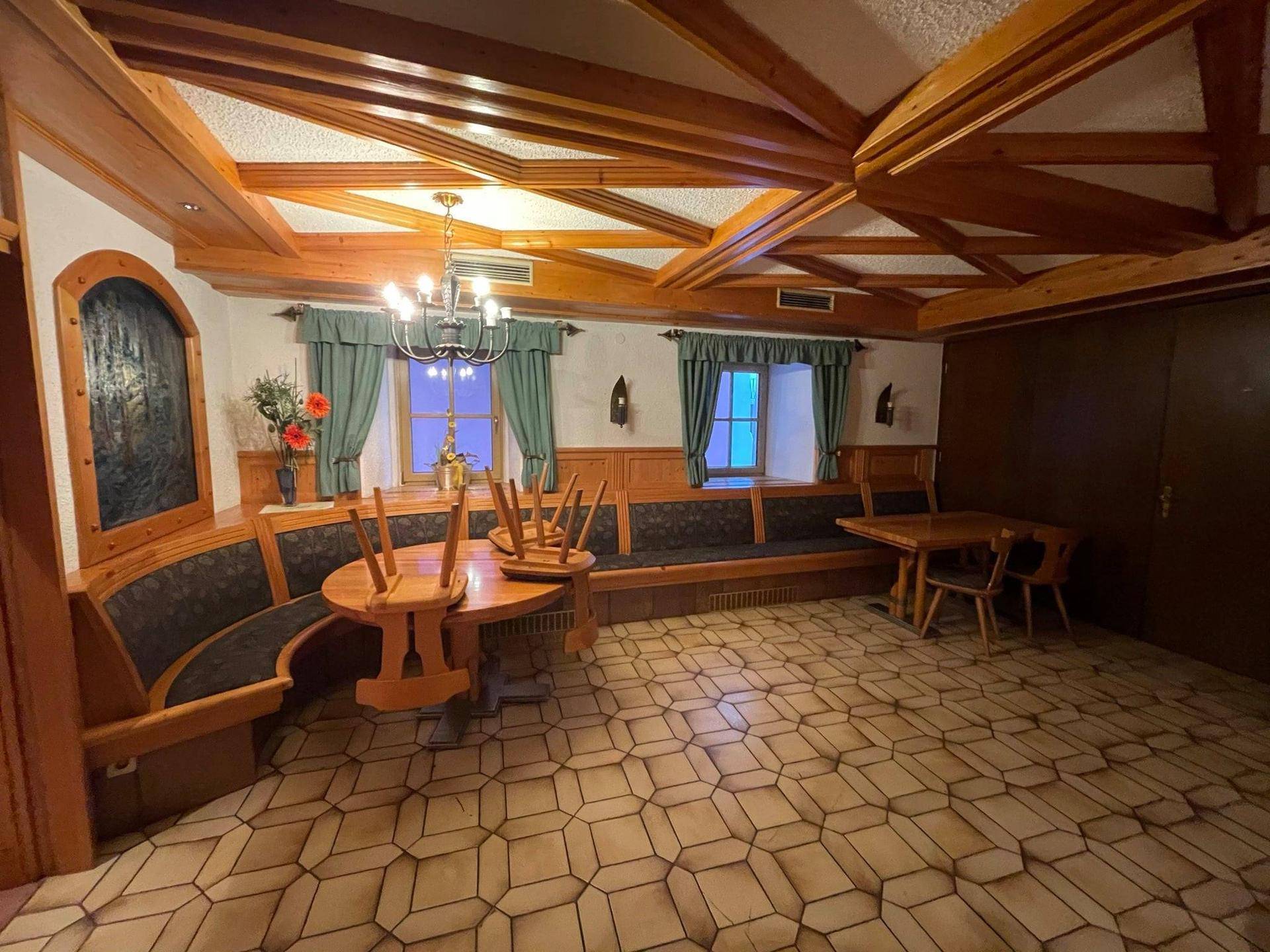 Traditioneller Speisesaal mit Holzbänken und gestapelten Tischen, bereit für die nächste Nutzung.