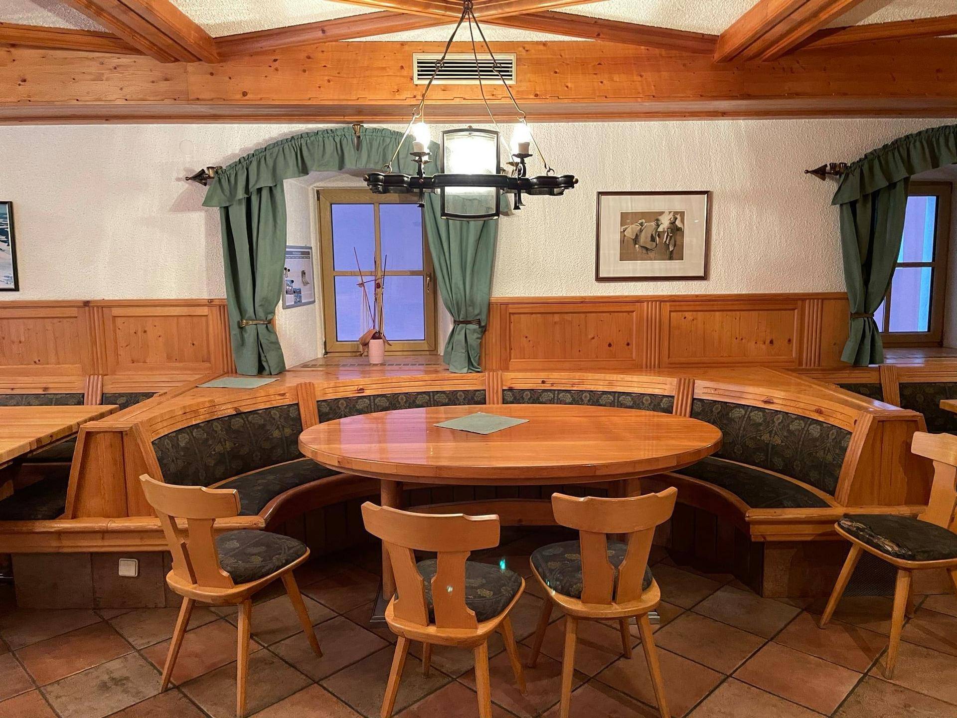 Gemütlicher Essbereich mit runden Holztischen, gepolsterten Bänken und traditioneller Einrichtung.