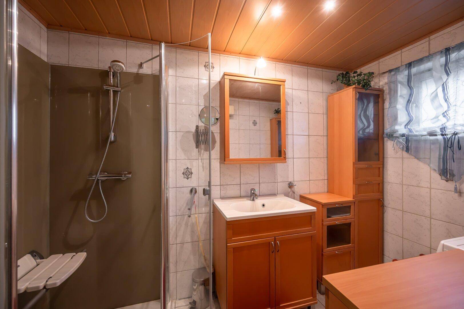 Badezimmer mit Duschkabine, Waschbecken und Fliesenwänden, funktional und hell.