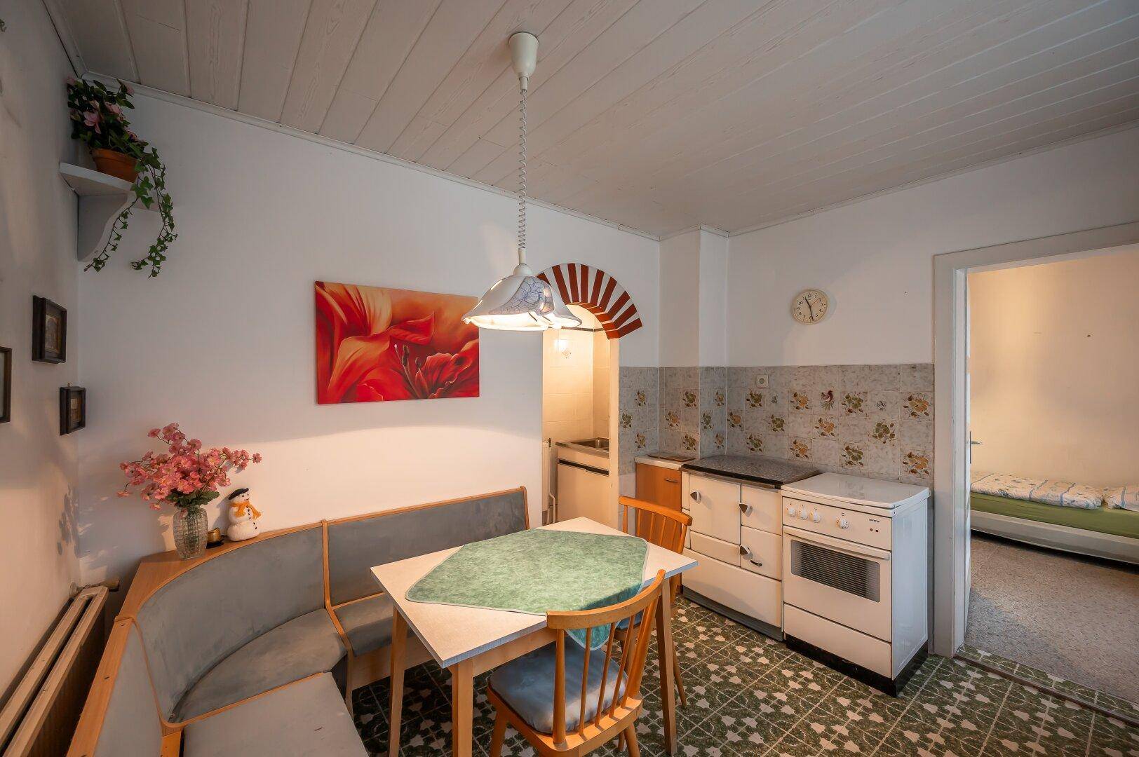 Kleine Küche mit Essecke, traditionellem Herd und Zugang zu einem angrenzenden Schlafzimmer.