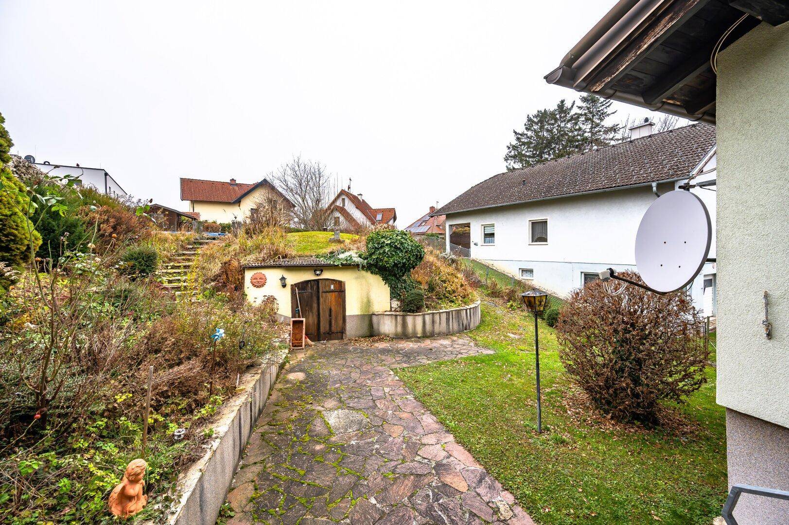 Außenansicht des Anwesens mit Erdkeller, Gartenbereich und dem Haupthaus im Hintergrund.