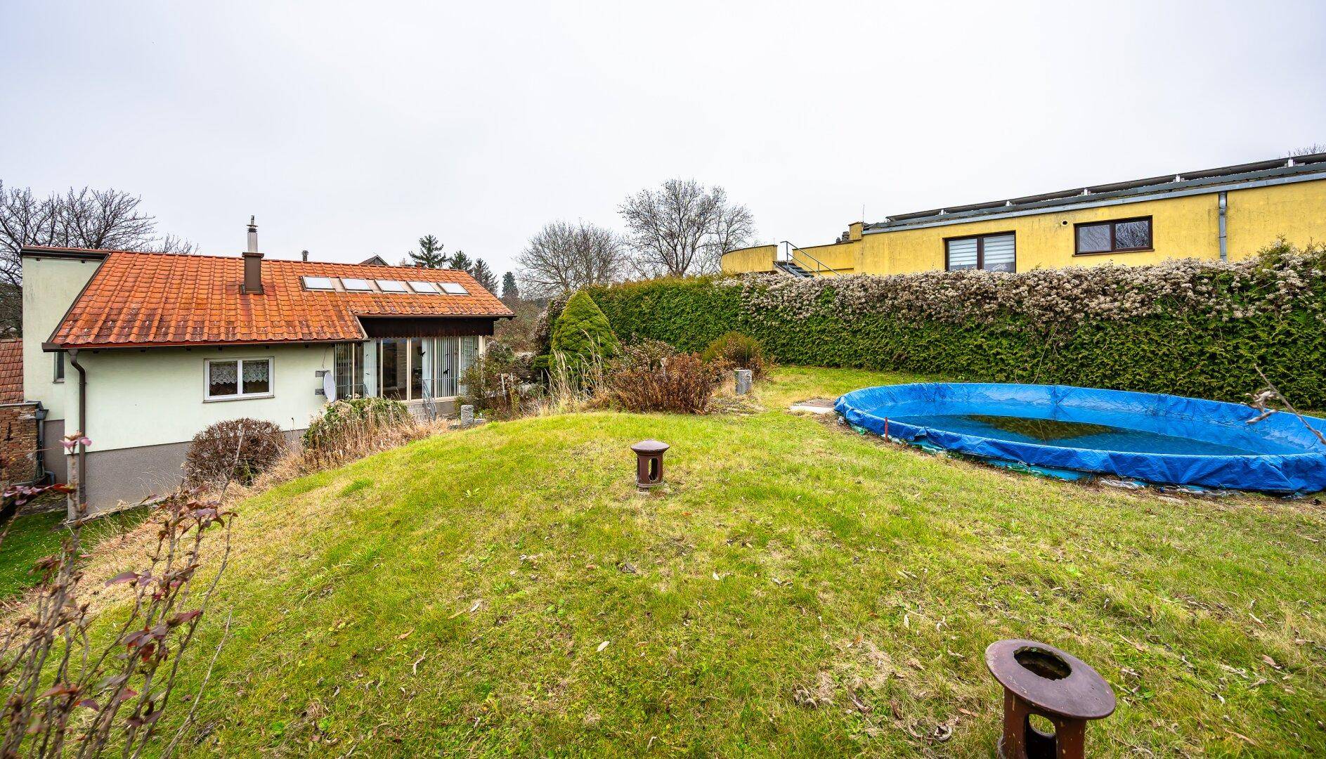 Gartenansicht von oben mit Rasenfläche, oberirdischem Pool und dem Wohnhaus im Hintergrund.