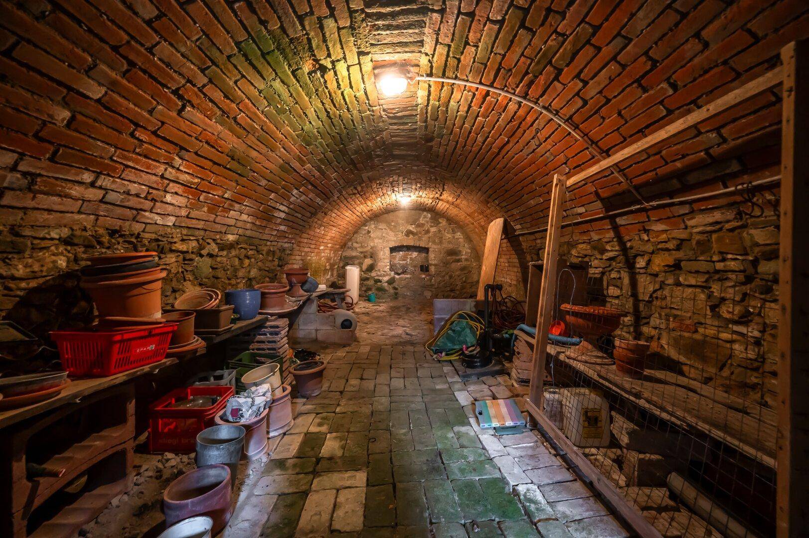 Historischer Gewölbekeller aus Ziegelsteinen mit Lagerflächen, ideal für Wein oder Vorräte.