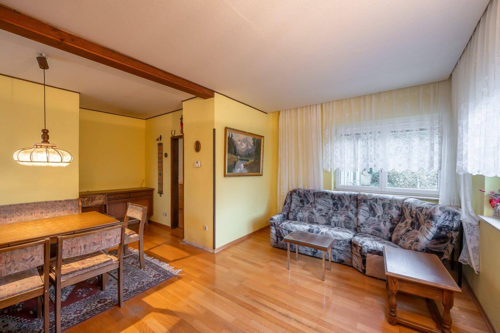 Heller Wohn-Essbereich mit Holzboden, Sofa und Esstisch, ideal für geselliges Beisammensein.