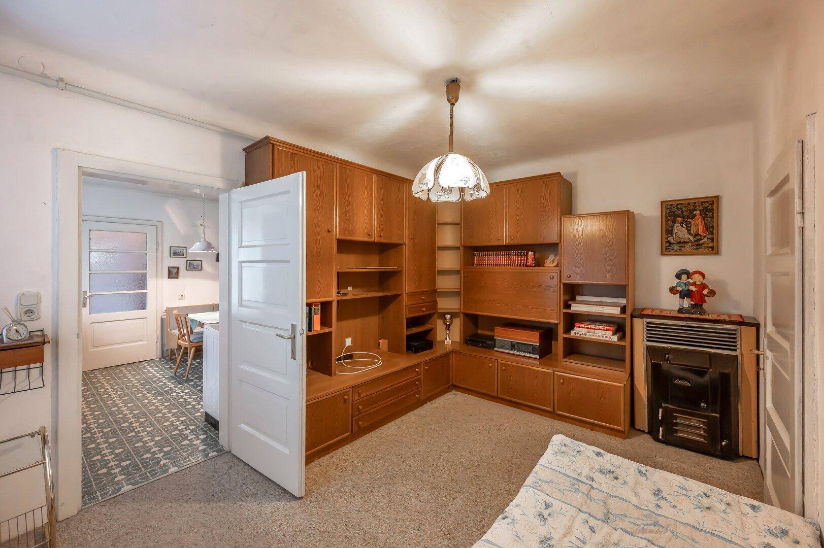 Schlafzimmer mit großem Wandschrank, Bett und Teppichboden, verbunden mit der Küche.