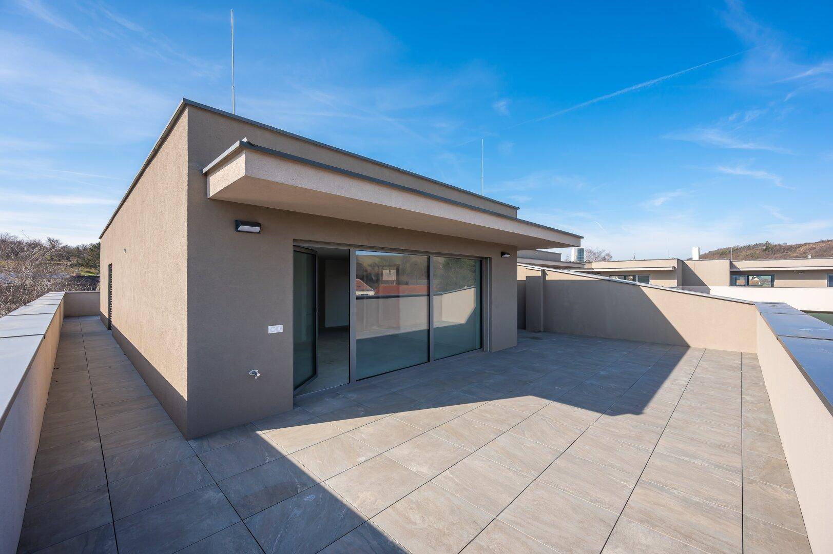 Moderne Dachterrasse mit klaren Linien und weitem Blick unter strahlend blauem Himmel.
