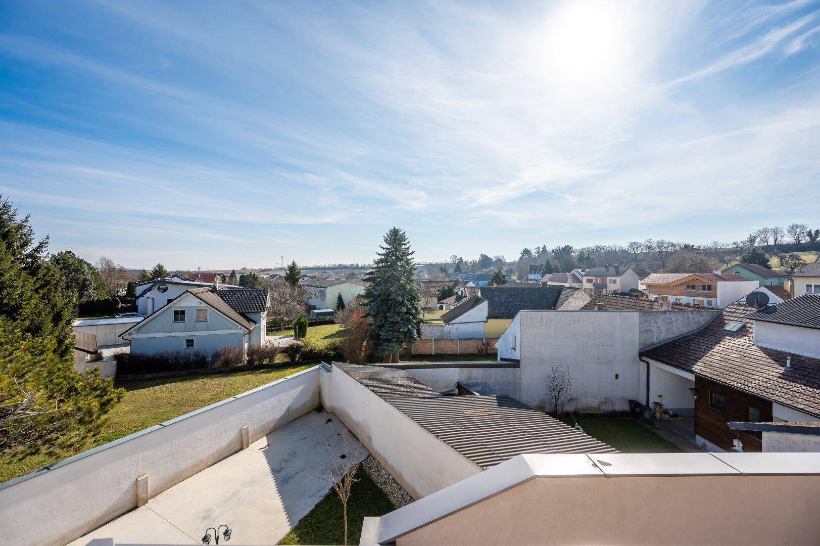 Weitläufiger Blick über eine Wohnsiedlung mit viel Grün und blauen Himmel.