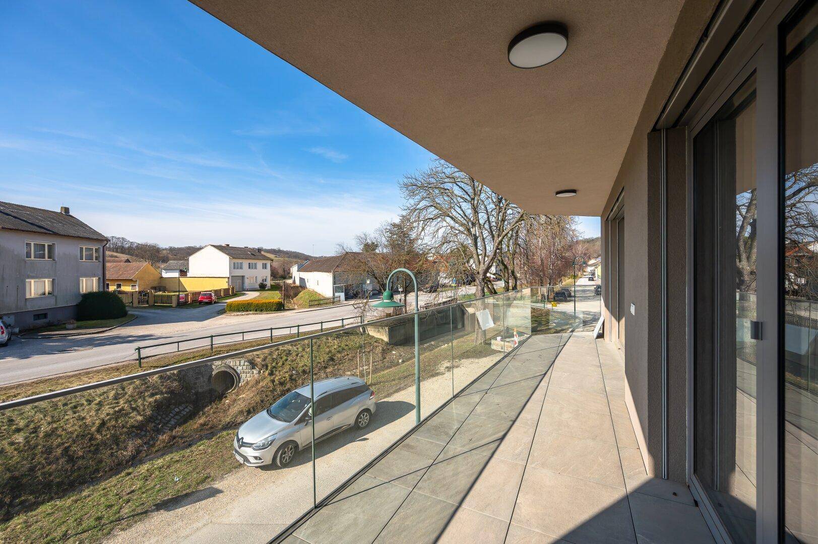 Langer, schmaler Balkon mit Glasgeländer und Blick auf die Straße und die umliegende Landschaft.