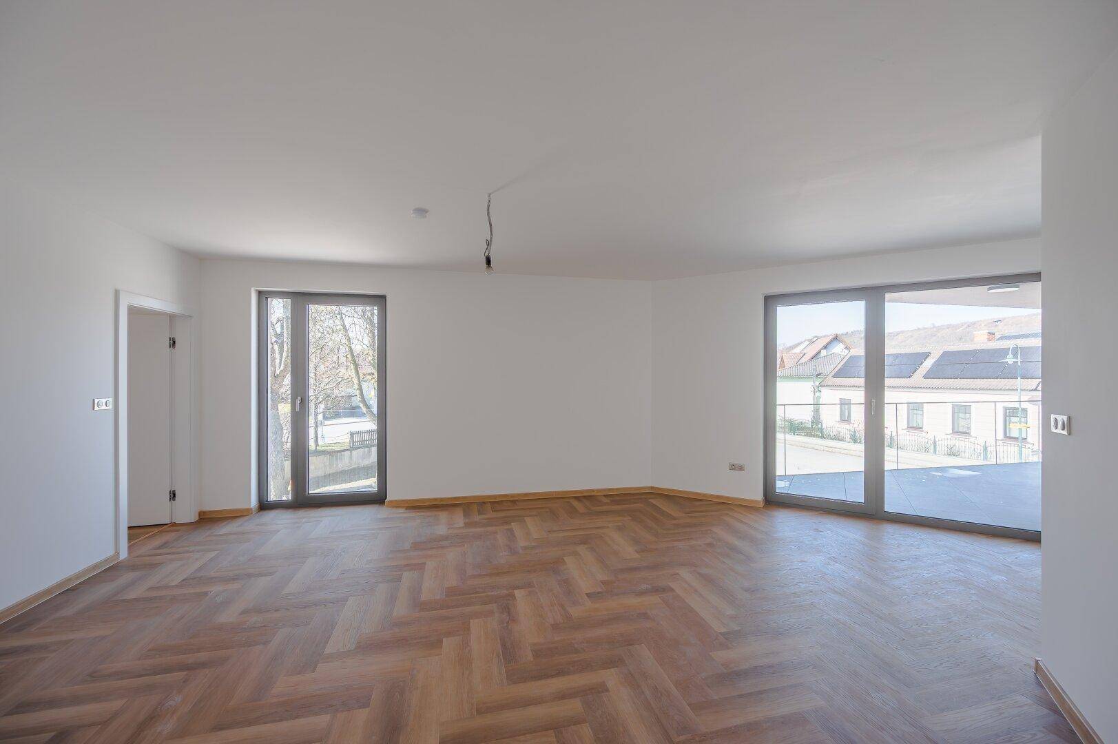 Geräumiges Zimmer mit elegantem Fischgrätparkett und Zugang zu zwei Außenterrassen.