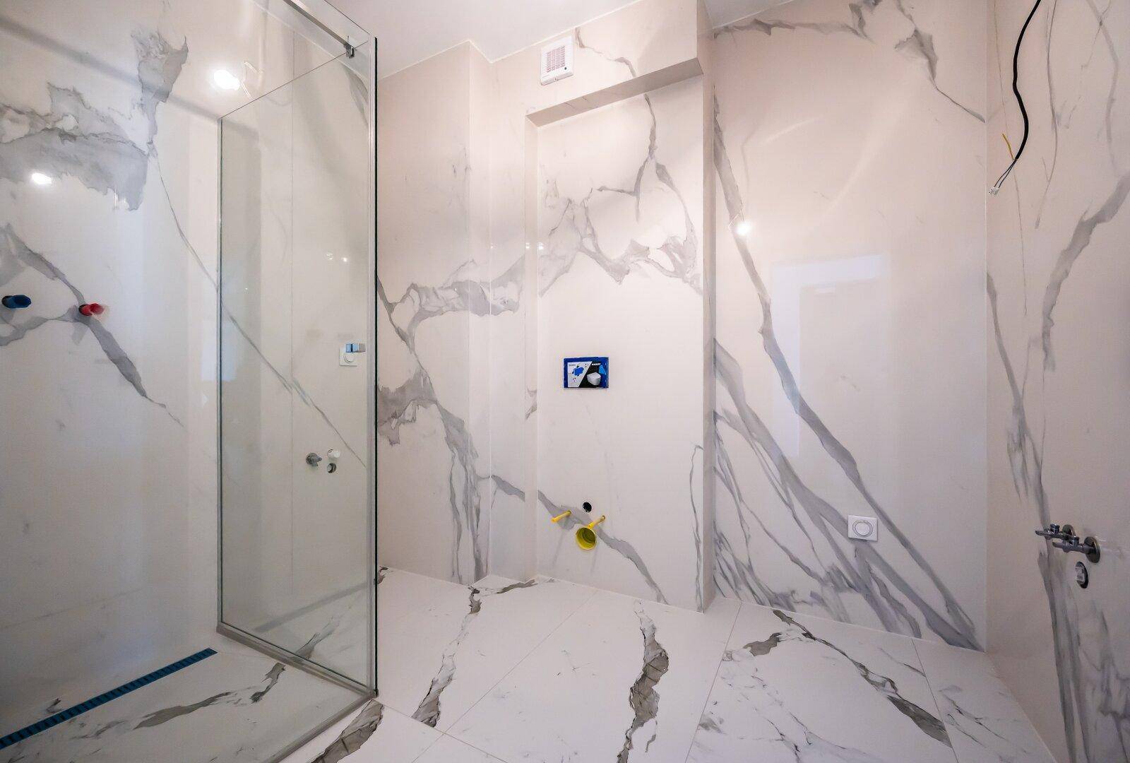 Modernes Badezimmer im Bau mit großformatigen Marmorfliesen und begehbarer Dusche.