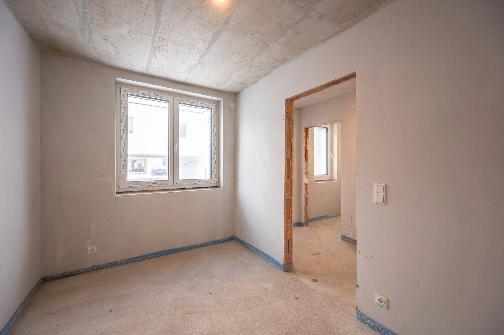 Schlafzimmer im Rohbau mit zwei Fenstern für viel Tageslicht.