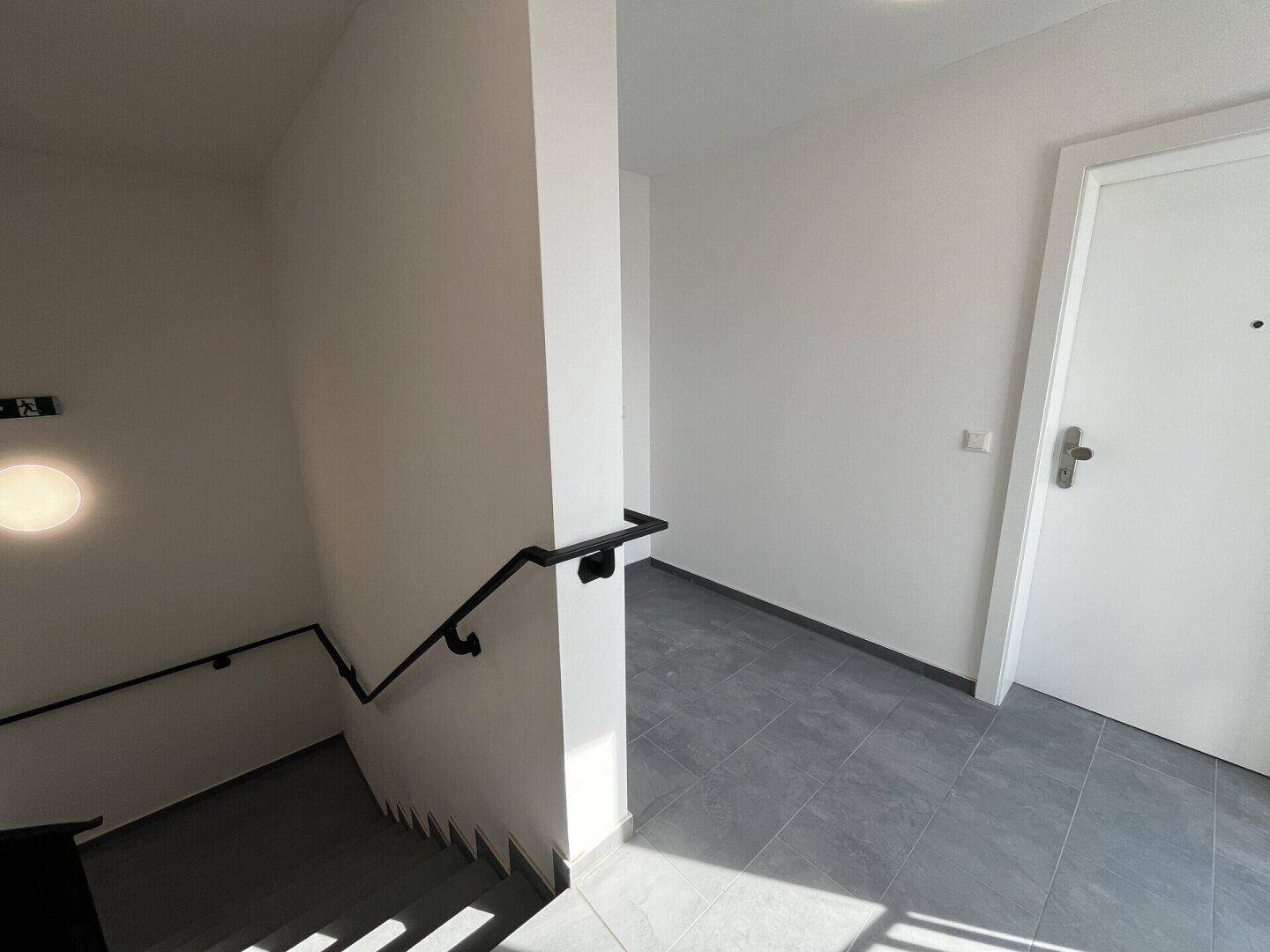 Heller Eingangsbereich mit Fliesenboden und Zugang zum Treppenhaus.