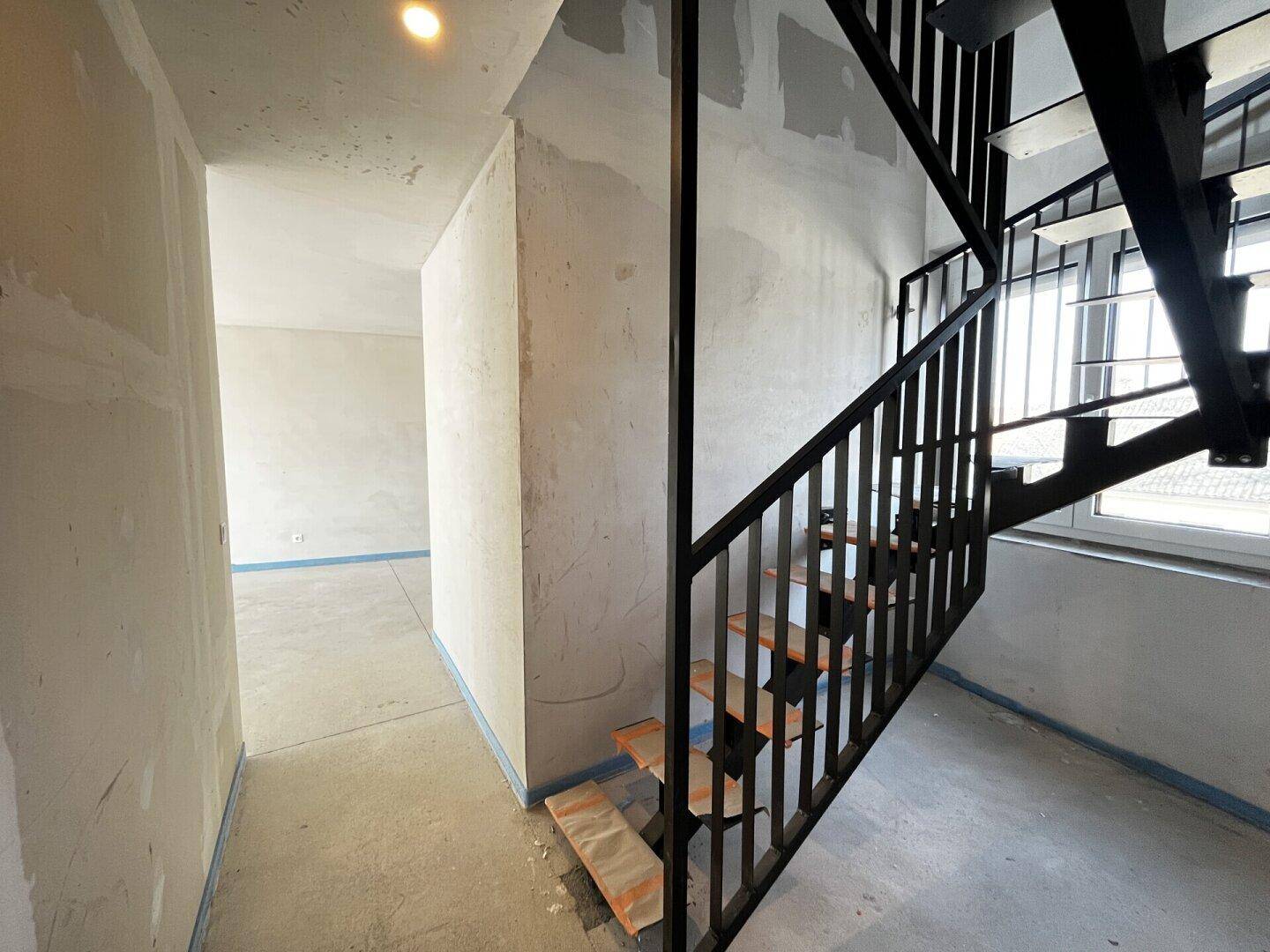 Treppenhaus im Bau mit offener Treppe und Metallgeländer.