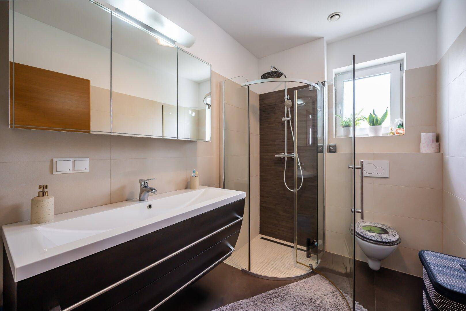 Modernes Badezimmer mit Dusche, Einzelwaschbecken und Fenster für Tageslicht.