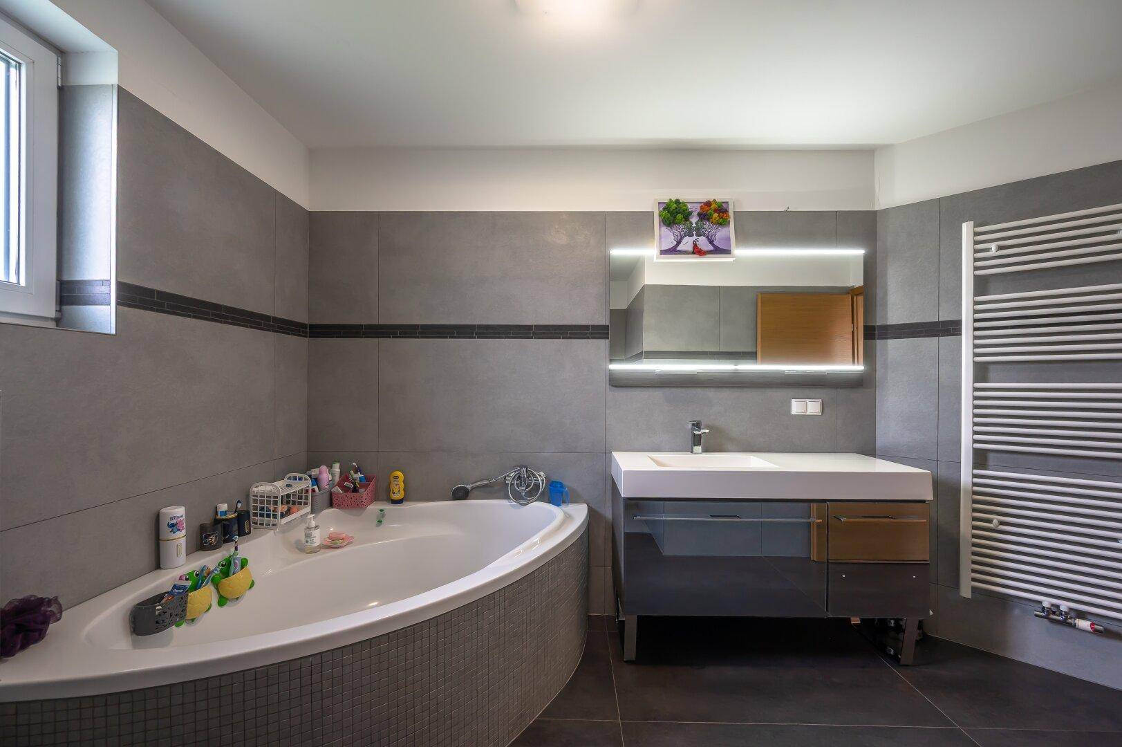 Geräumiges Badezimmer mit Eckbadewanne, modernem Waschtisch und beheiztem Handtuchhalter.