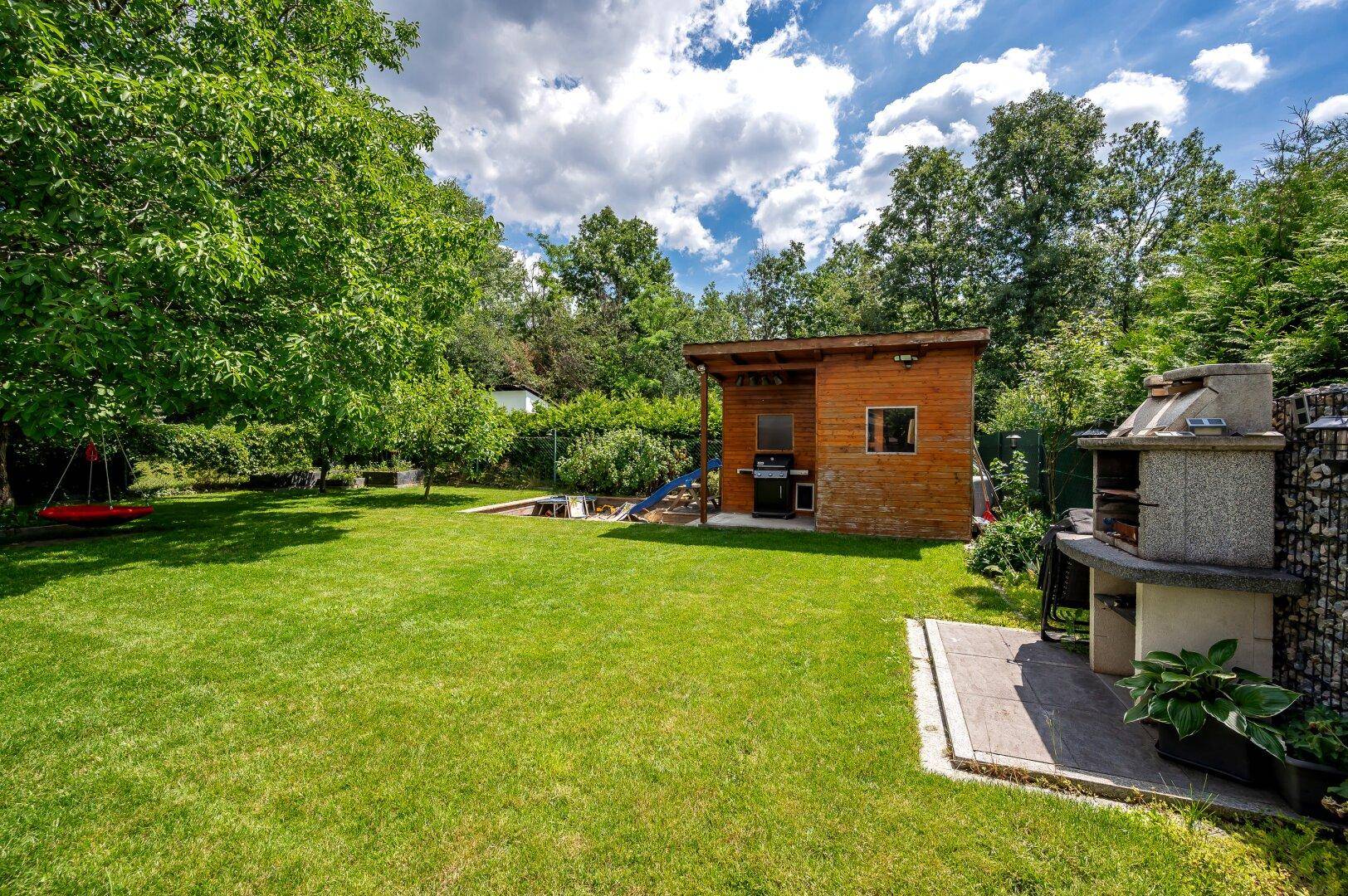 Gepflegter Garten mit gemauertem Grill, Holzgartenhaus und viel Rasenfläche für Freizeitaktivitäten.
