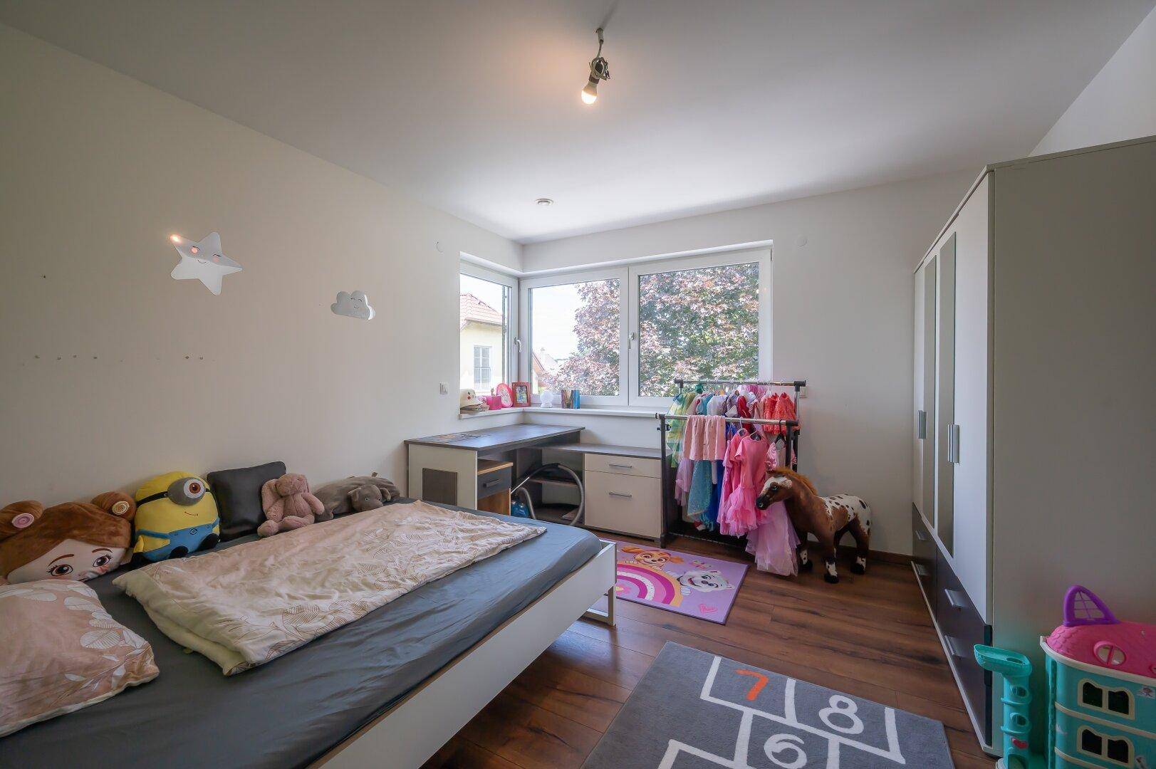 Kinderzimmer mit Bett, Schreibtisch und Kleiderschrank, hell und freundlich gestaltet.