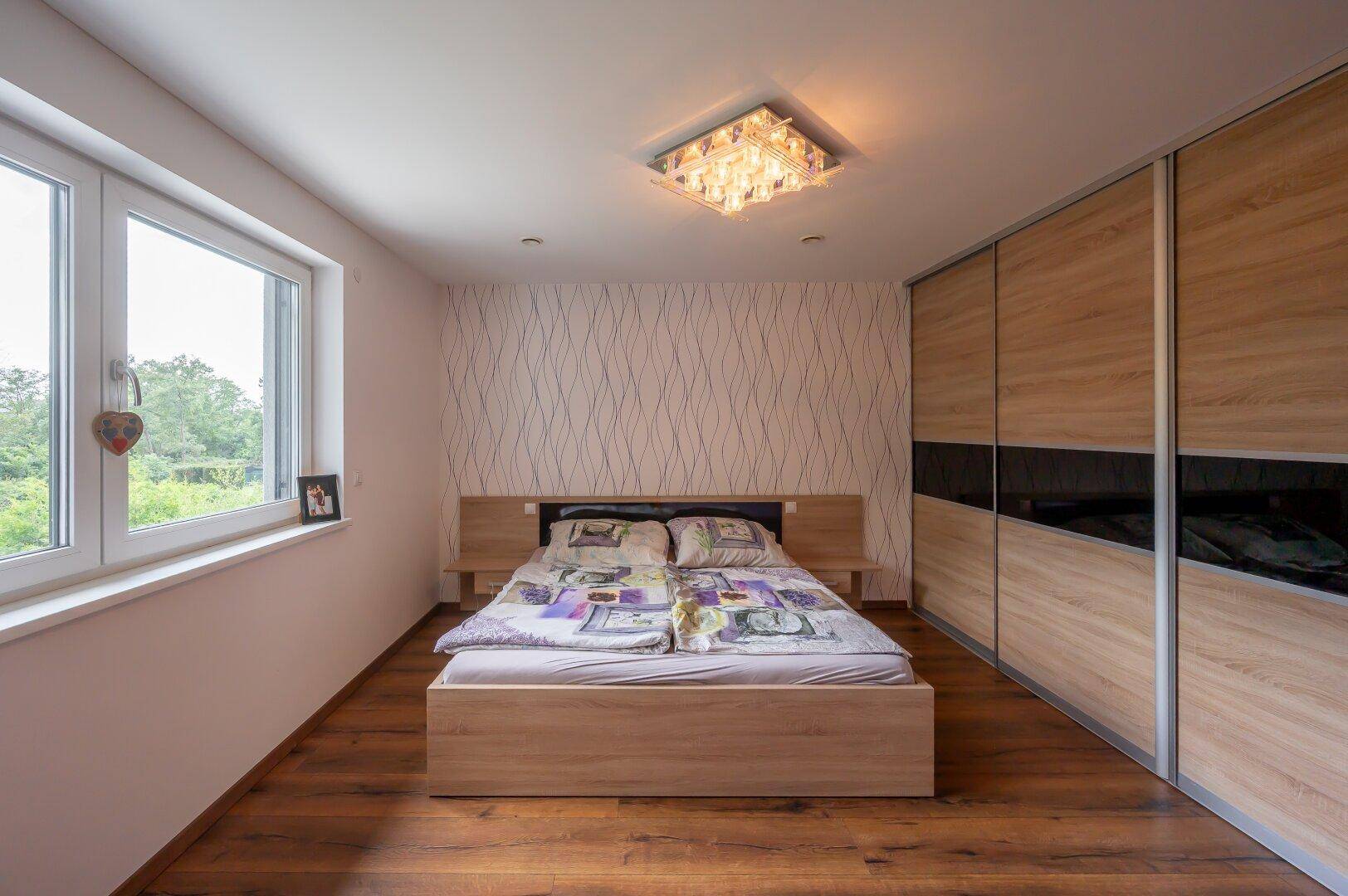 Geräumiges Schlafzimmer mit Doppelbett, Einbauschränken und großen Fenstern.