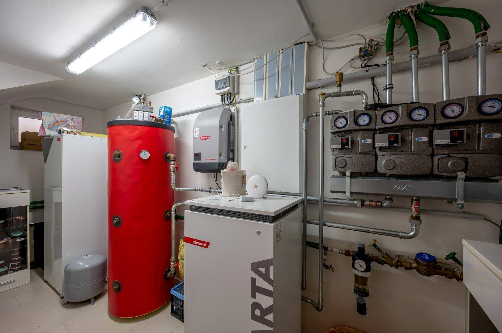Technikraum im Keller mit Heizungsanlage, Warmwasserspeicher und verschiedenen Installationen.