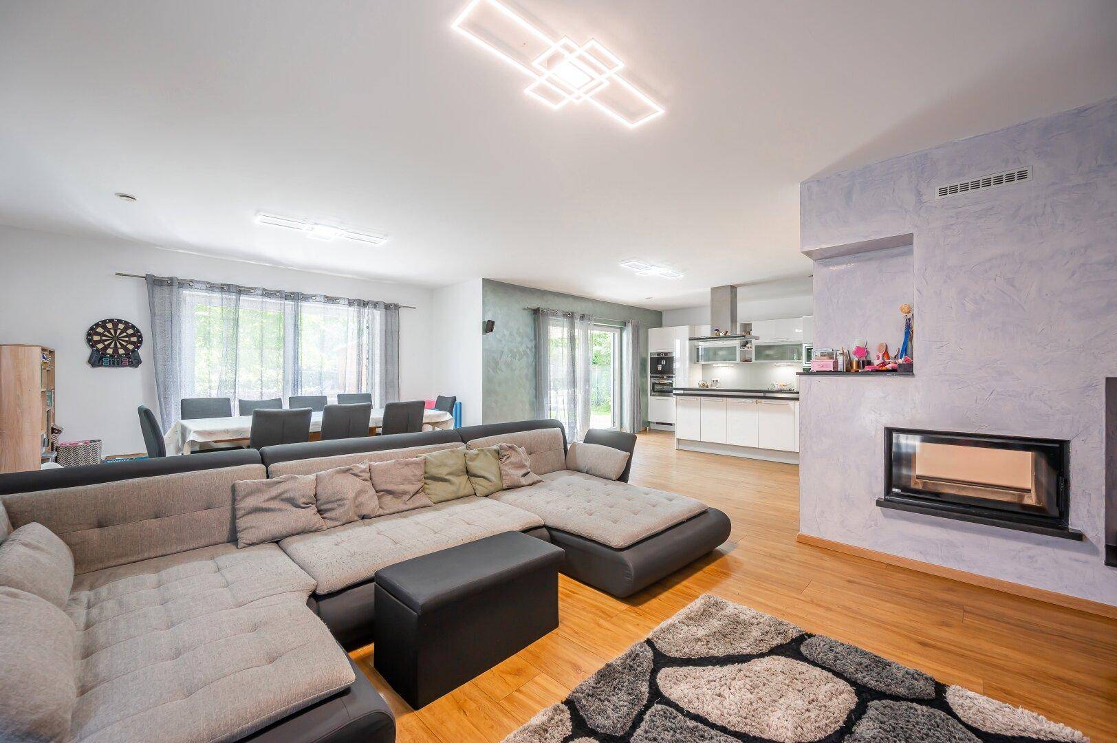 Geräumiger Wohn-Essbereich mit großem Sofa, Kamin und offener Verbindung zur Küche.